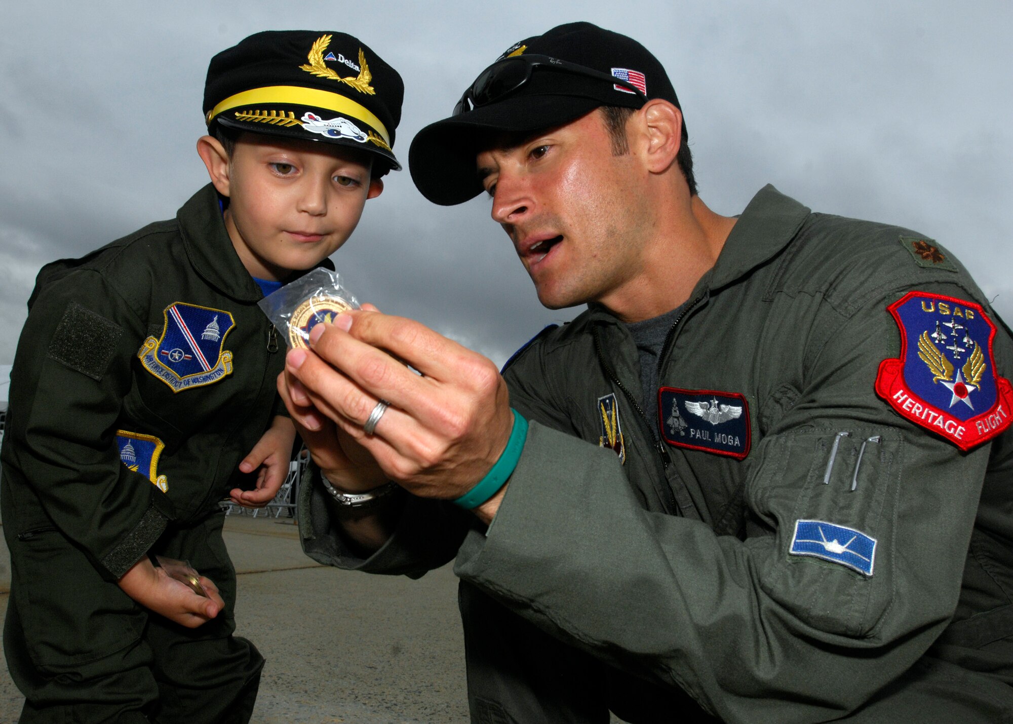 Major Paul Moga, F22 Raptor Team Pilot, explains to Brandon Leach, Pilot for a day, the significance of the coin he was giving him at the 2008 Joint Service Open House on Andrews AFB, MD 16 May 2008. (USAF Photo by Senior Airman Melissa Stonecipher)