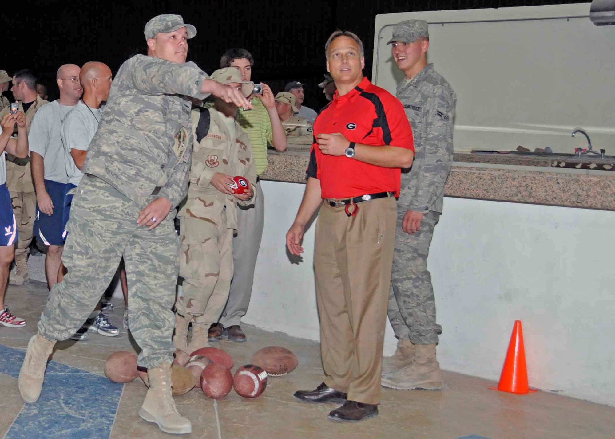 An Airman tries the "Quarterback Challenge" with encouragement from Mark Richt, the University of Georgia head coach, while waiting in line for autographs from the five NCAA coaches who visited the base May 22. (U.S. Air Force photo/Senior Airman Domonique Simmons) 
