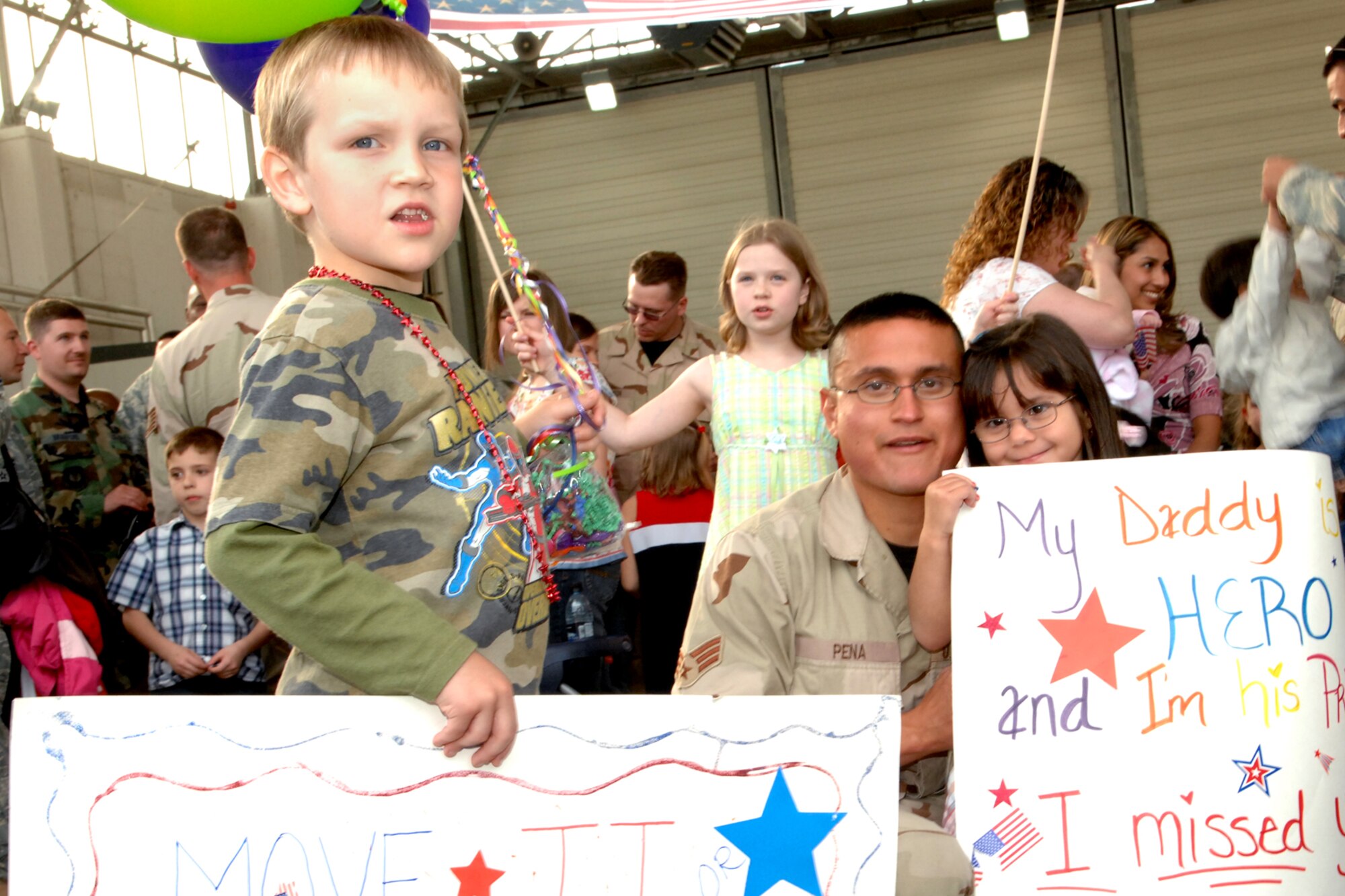SPANGDAHLEM AIR BASE, Germany--  Senior Airman Michael Pena, 81st Fighter Squadron, poses with his children as they hold signs made by his family for his return from his 121-day deployment to Bagram Air Base, Afghanistan, May 20, 2008.  U.S. Air Force photo by Senior Airman Logan Tuttle.