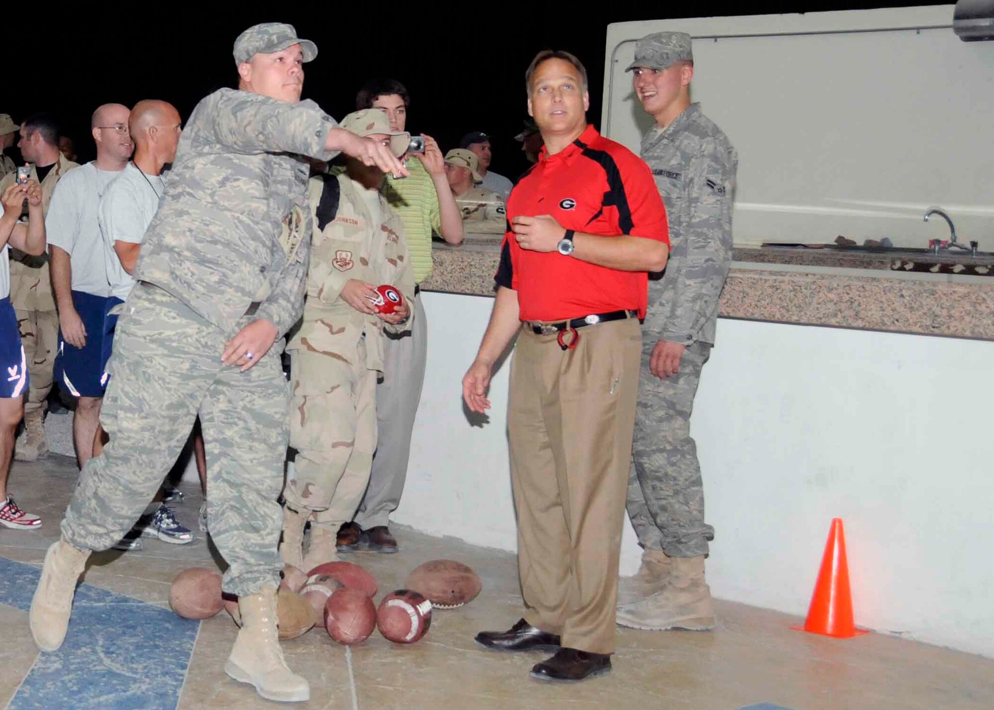 SOUTHWEST ASIA -- An Airman tries the “Quarterback Challenge” with encouragement from Mark Richt, the University of Georgia head coach, while waiting in line for autographs from the five NCAA coaches who visited the base May 22. (U.S. AIR FORCE PHOTO BY SENIOR AIRMAN DOMONIQUE SIMMONS)