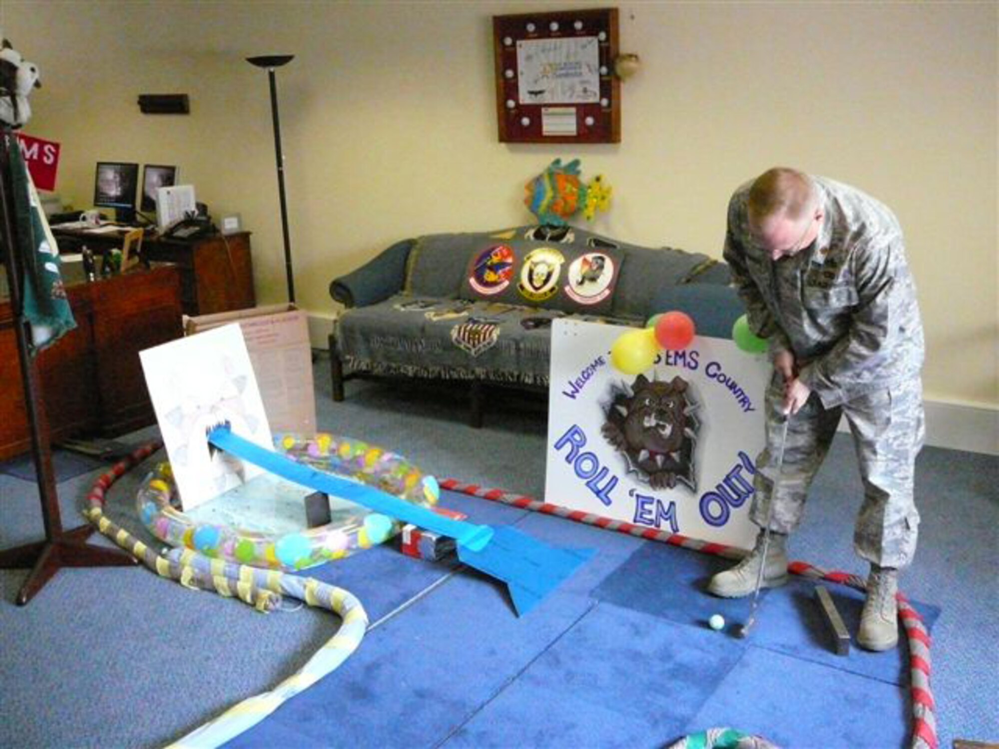 Major Darrin Dronoff, 48th Equipment Maintenance Squadron commander takes his shot into the Bulldog-themed hole in his office May 9 at RAF Lakenheath, England. Major Dronoff initiated a chili cook-off and golf challenge to help boost morale and earn funds for a newly founded spouses' group. (Photo provided by Tech. Sgt. Brian Klemp)