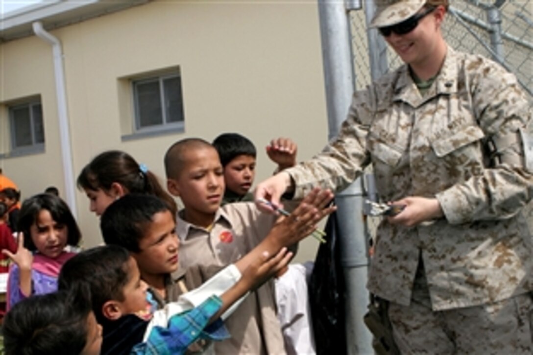 U.S. Navy Lt. Dana Cash hands out school supplies to local children outside the hospital on Camp Hero, Afghanistan, May 22, 2008. Cash is  a medical officer assigned to the Combat Logistics Battalion 24, 24th Marine Expeditionary Unit, NATO International Security Assistance Force.