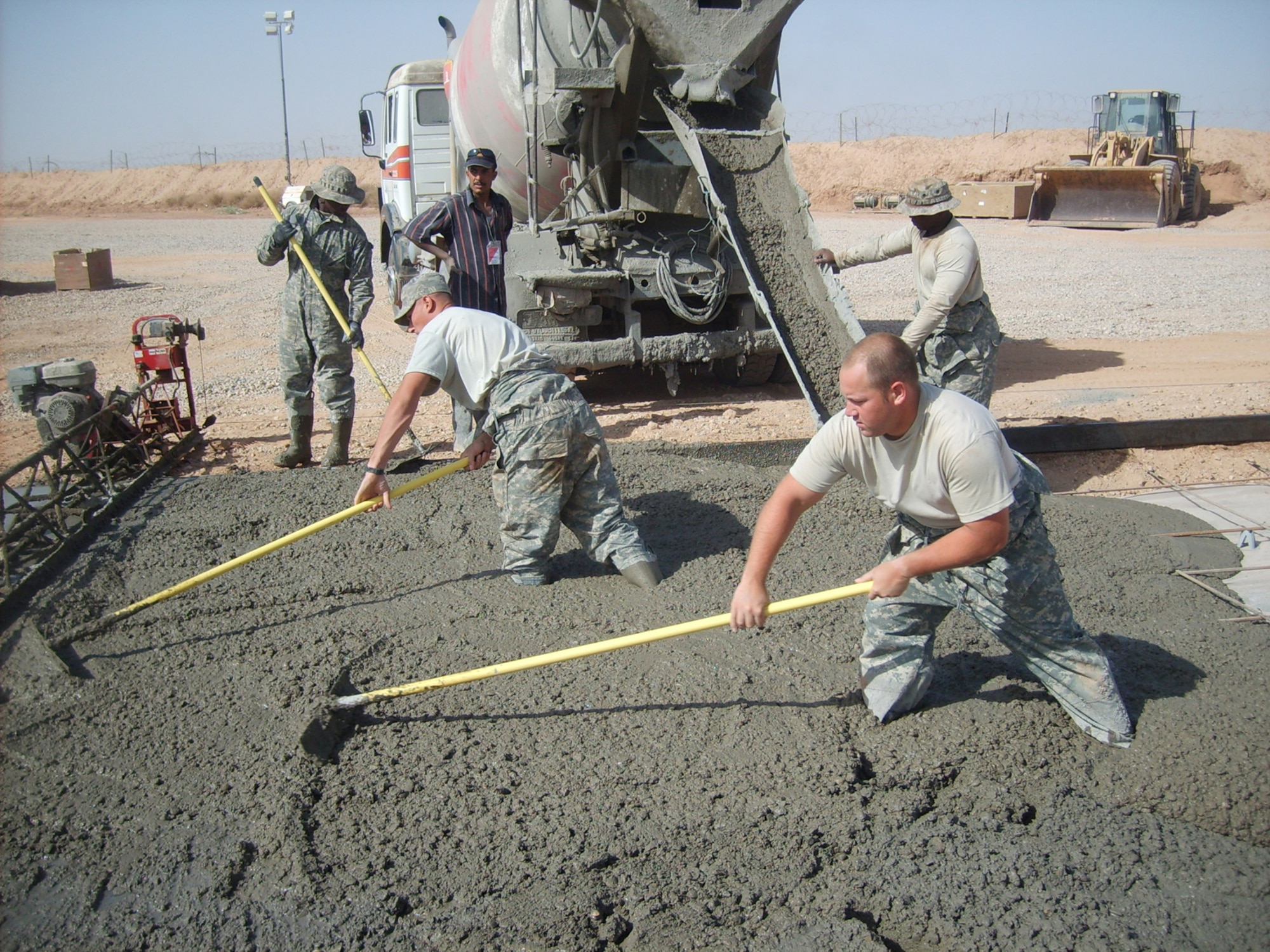 BALAD AIR BASE, Iraq -- Senior Airmen Dan Smith and Deion Williams and Airmen 1st Class George Farrington and Richard Simmons, 732nd Expeditionary Civil Engineer Squadron heavy equipment operators, Dirt Boyz section, pour and rake concrete pads during a project to improve Forward Operating Base Caldwell, Iraq. The concrete pads will allow Soldiers to perform maintenance on their vehicles without having to lay in the mud. (U.S. Air Force photo/ Staff Sgt. Josh Jeffreys)