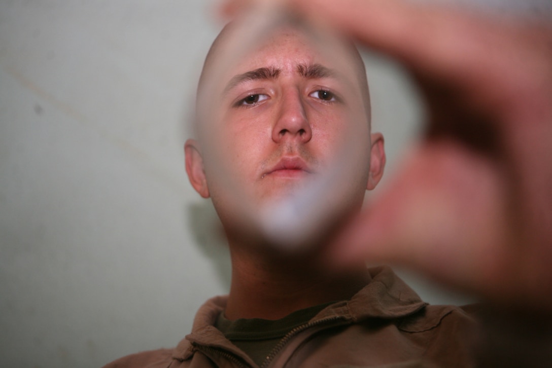 Looking through a split deck of playing cards, Pfc. Kyle D. Alders, a scout with Charlie Company, 2nd Light Armored Reconnaissance Battalion, Regimental Combat Team 5, demonstrates one of the many card tricks he has mastered at Camp Korean Village, Iraq, May 23. The 19-year-old from West Palm Beach, Fla., helped create a device that would help a world community of approximately 40 million people, the blind and visually impaired.