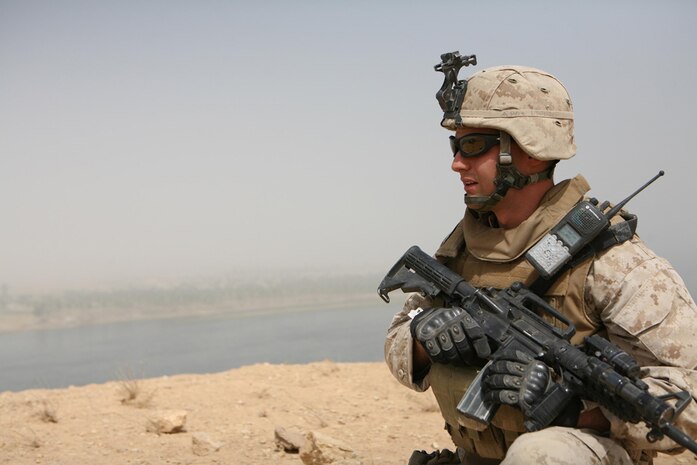 Lance Cpl. Jordan R. Brand, 21, a machine gunner from Papillion, Neb., assigned to Company L, 3rd Battalion, 4th Marine Regiment, Regimental Combat Team 5, provides security while Marines with Company L patrol the Euphrates River on boats May 25. Marines on the shore provided security for Marines conducting cache sweeps on islands in the river near Haditha, Iraq.