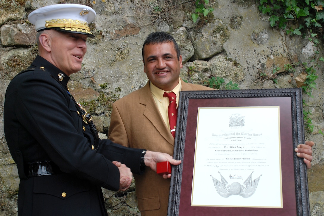 Commandant of the Marine Corps Gen. James T. Conway presents Gilles Lagin, Belleau Wood historian, with a certificate recognizing him as an Honorary Marine at the Bulldog Fountain in Belleau, France, May 25. Lagin becomes one of a few non-U.S. citizens to earn the title honorary Marine for his life-long dedication to preserving the history of the Marines who fought in Belleau Wood during World War I.