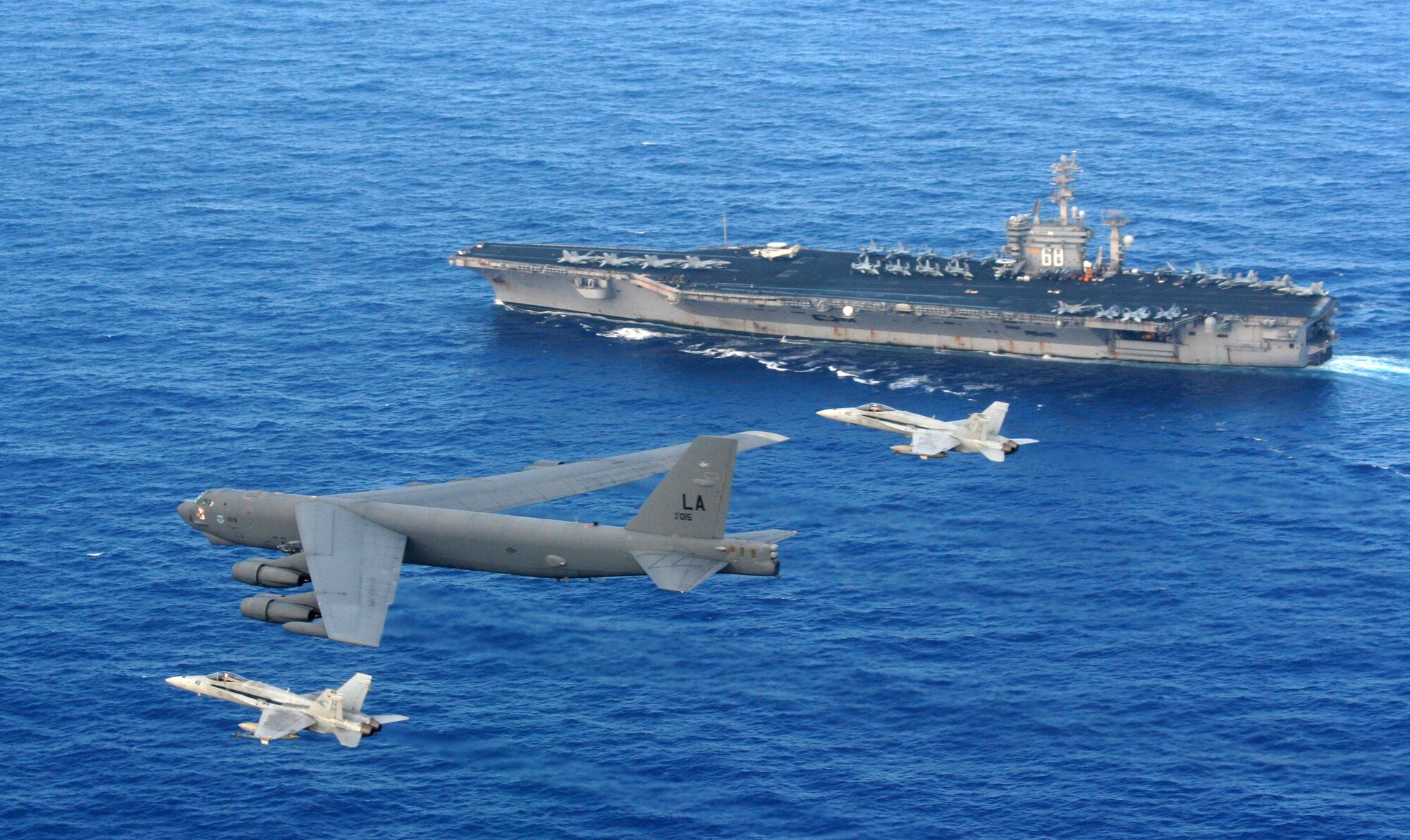 Two F/A-18 Hornets intercept a B-52 Stratofortress while it is performing a rigging maneuver to identify the USS Nimitz below, during the first week of May. The B-52 is from the 96th Expeditionary Bomb Squadron currently deployed to Andersen Air Force Base, Guam as part of the continuous bomber presence. (Courtesy photo by US Navy)
