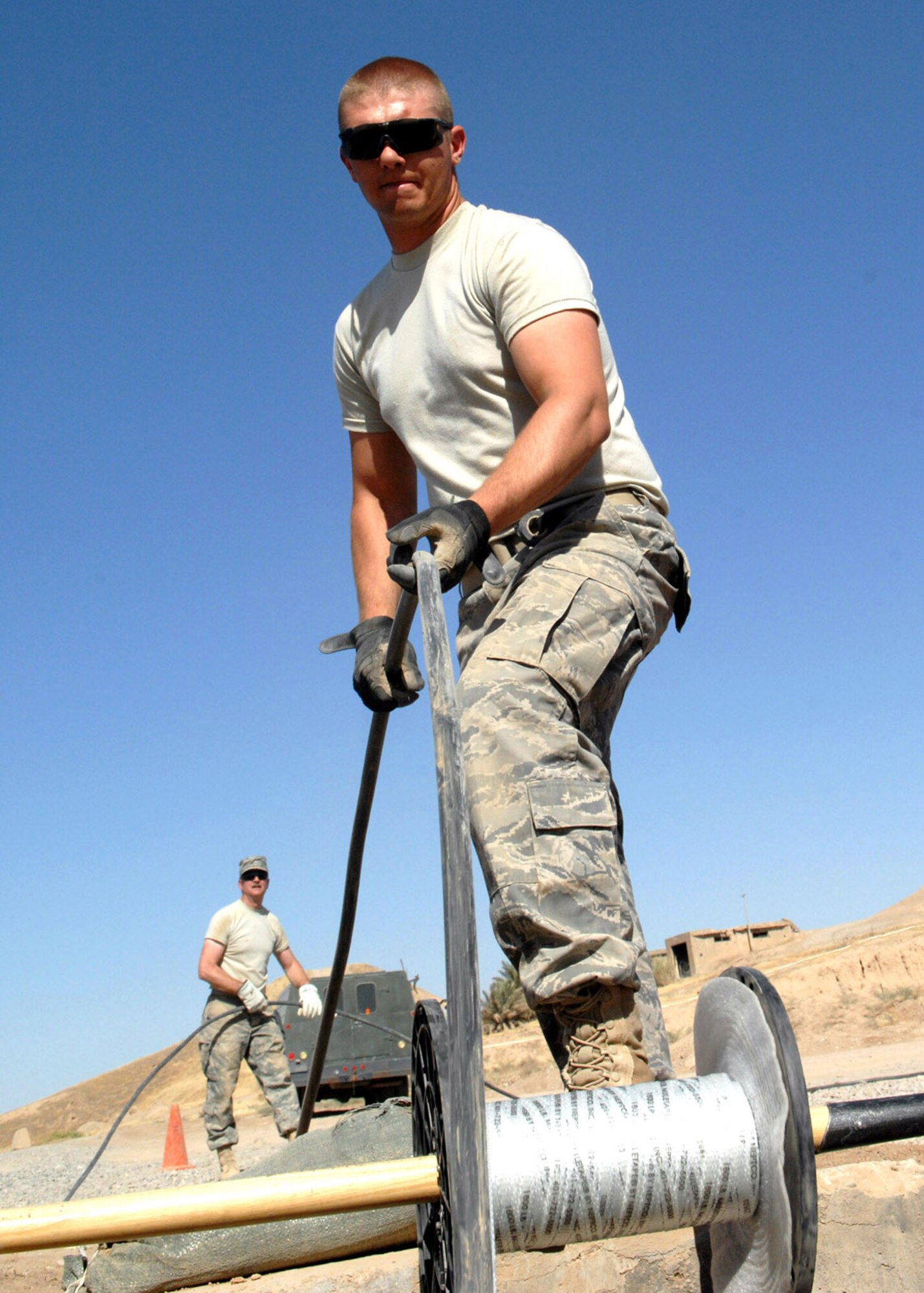 KIRKUK REGIONAL AIR BASE, Iraq – Senior Airman Aaron Wilson (front) and Master Sgt. Doug Snider, 506th Expeditionary Communications Squadron, install a telephone cable in a manhole to improve communications security May 23 here. Airman Wilson is a native of Tulsa, Okla., and Sergeant Snider is a native of Dexter, Miss. (U.S. Air Force photo by Senior Airman SerMae Lampkin)
