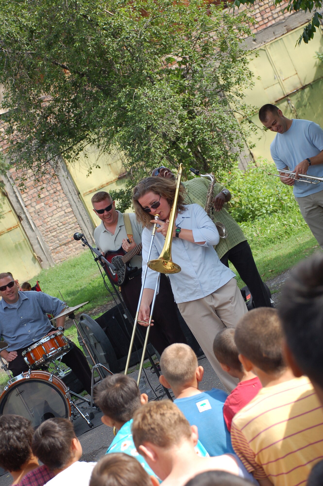 (08/05/25) MANAS AB, KYRGYZSTAN – Staff Sgt. Heather Kirschner, U.S. Air Forces Central Band Thunder Roll trombonist, demonstrates the range of the trombone at the Belovodosky Orphanage.  The AFCENT band performed at the orphanage and explained the different instruments the band uses during their visit.  (U.S. Air Force/TSgt Jerome Baysmore/ Released)