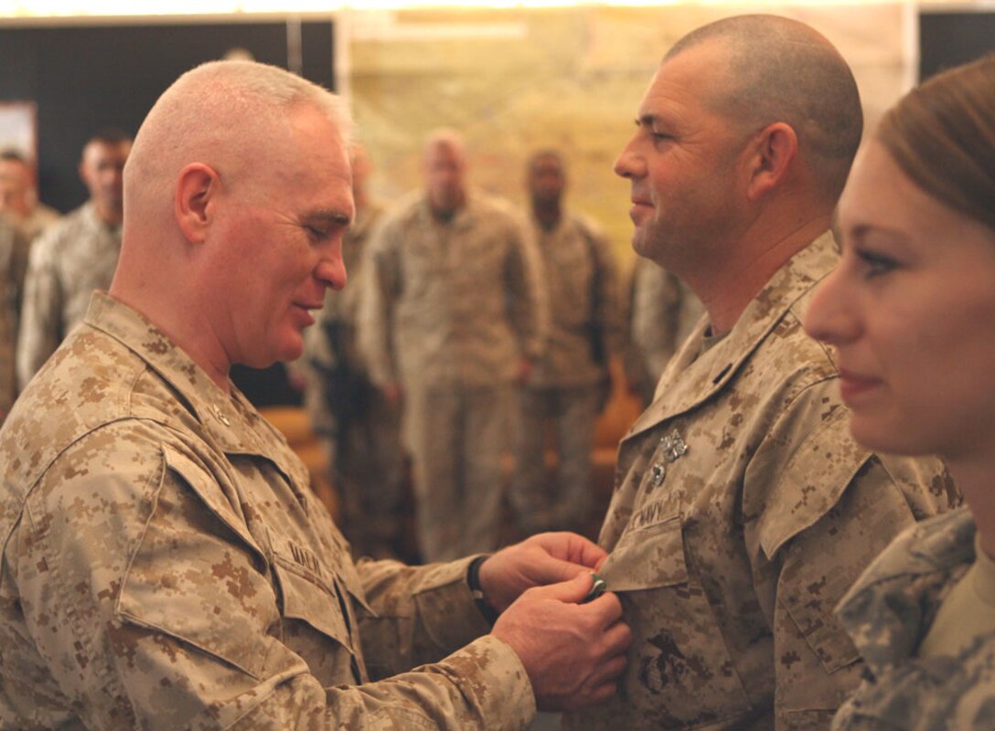 Col. Patrick Malay, commanding officer, Regimental Combat Team 5, presents Navy Petty Officer 1st Class Boyd W. Lewis, 41, a religious program specialist with RCT-5 from Willisburg, Ky., the Navy and Marine Corps Commendation Medal during a ceremony Monday at Camp Ripper, Iraq. Lewis' superior performance as a religious program specialist, which entails providing worship services to Marines and sailors through the Al Anbar province, has warranted him this coveted award from the Marine Corps.