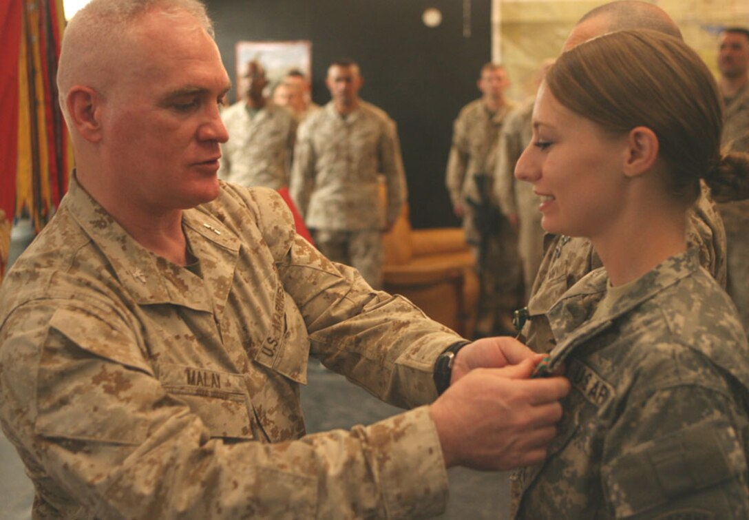 Col. Patrick Malay, commanding officer, Regimental Combat Team 5 presents Army Sgt. Jenny M. Neuhart, 25, who is from St. Louis, the Navy and Marine Corps Achievement Medal, during a ceremony Monday at Camp Ripper, Iraq. Neuhart, the women's engagement program director with the 307th Psychological Operations Company, RCT-5, played an intricate role in advancing the women's engagement program, which brings Iraqi women together to learn new skills across the Al Anbar province.