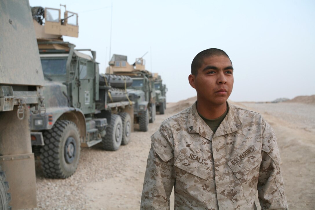 Lance Cpl. Brennan R. Beall, 22, an administrative clerk with 3rd Battalion, 4th Marine Regiment, Regimental Combat Team 5, from Many Farms, Ariz., stands in front of seven-ton trucks at Combat Outpost Haditha, Iraq, May 26. Beall, and other Marines from communications, supply and administration, have been serving as machine gunners for Truck Platoon, 3rd Bn., 4th Marines during the battalionâ??s deployment. He has enjoyed his new duties as convoy security for supply runs.