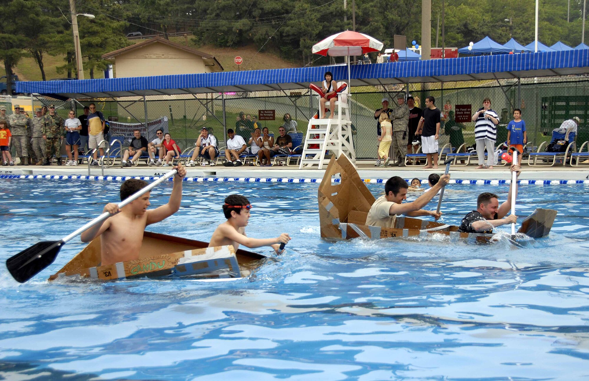 OSAN AIR BASE, Republic of Korea – Staff Sgt. Erik Milton and Staff Sgt. Miguel Reynoso, 51st Medical Support Squadron biomedical equipment repair technicians, edge out their competition during the build-a-boat contest at the base’s outdoor pool May 23. The contest was held in conjunction with the 51st Fighter Wing’s 101 Critical Days of Summer burger burn. (U.S. Air Force photo/Senior Airman Christopher Boitz)