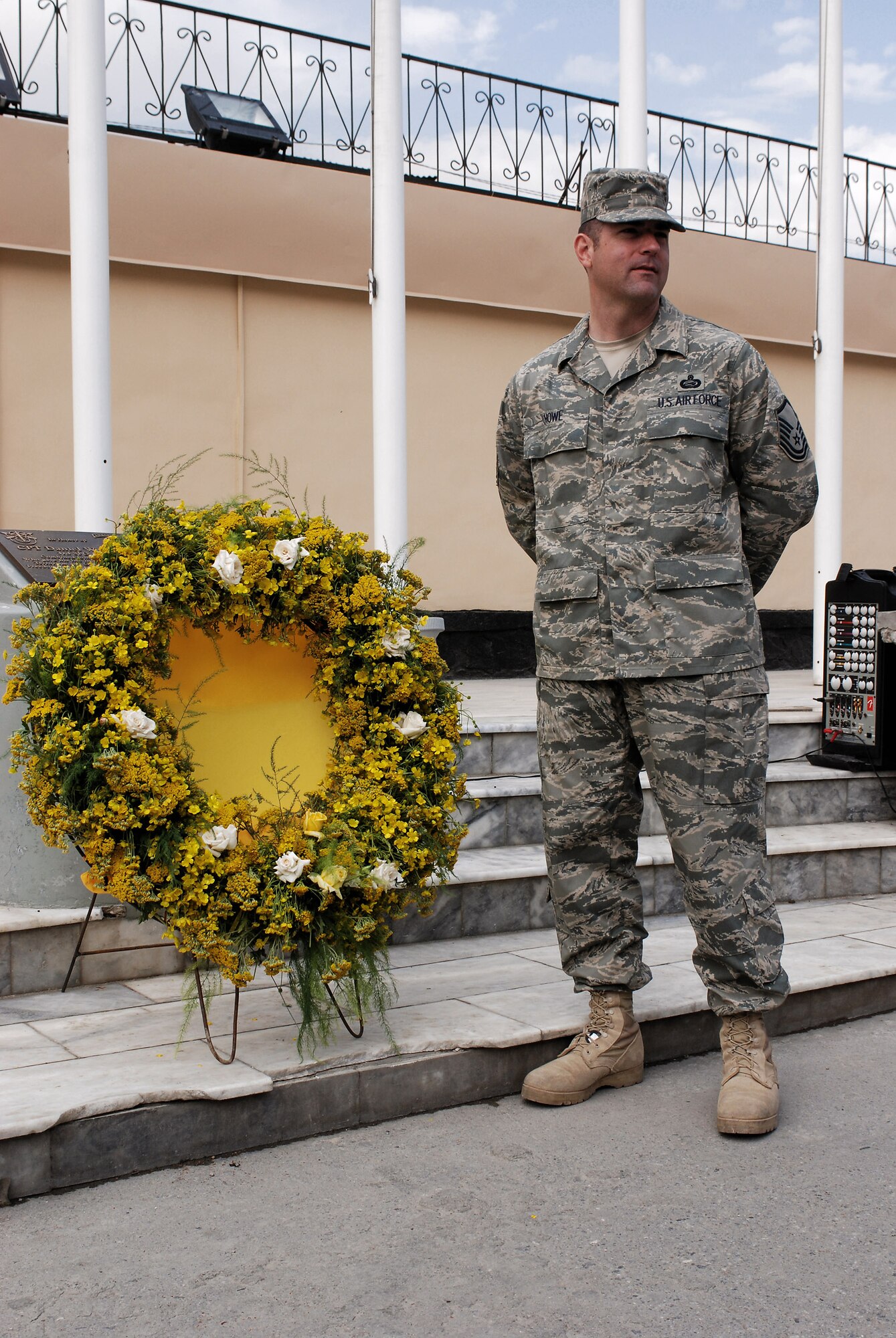 Master Sgt. John Howe, Combined Security Transition Command-Afghanistan personnel sergeant, stands next to a wreath displayed for a Memorial Day ceremony May 26 at Camp Eggers in Kabul, Afghanistan. Sergeant Howe, deployed from Elemendorf Air Force Base, Alaska, narrated the event. (U.S. Air Force photo/Petty Officer 1st Class Douglas Mappin)
