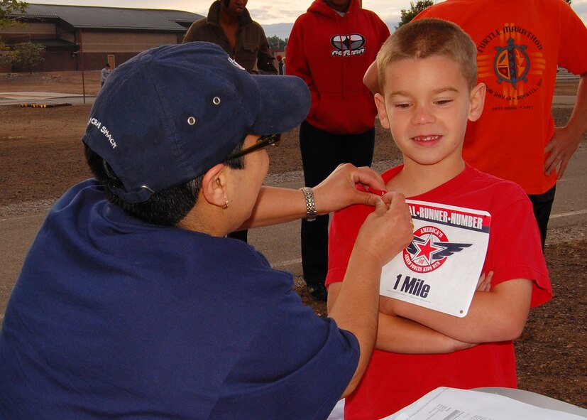Ms. Genevieve Melon, youth programs director, pins on CJ Thueson's runners bib for America's Kids Run at the base fitness center on Holloman Air Force Base, N.M.,  May 17. CJ ran in the 7 to 8 year old category which was one mile. (U.S. Air Force photo/Airman 1st Class Michael Means)