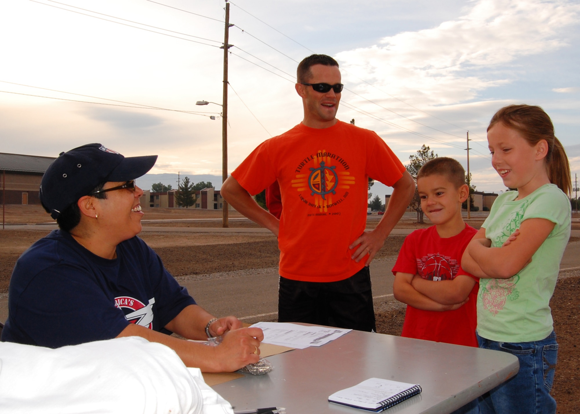 Ms. Genevieve Melon, youth programs director, signs in Staff Sgt. Jake Thueson, 49th Maintenance Operations Squadron  and his children CJ and Hannah Thueson for America's Kids Run at the base fitness center on Holloman Air Force Base, N.M.,  May 17. America's Kids Run offers many running categories for children of all ages. (U.S. Air Force photo/Airman 1st Class Michael Means)