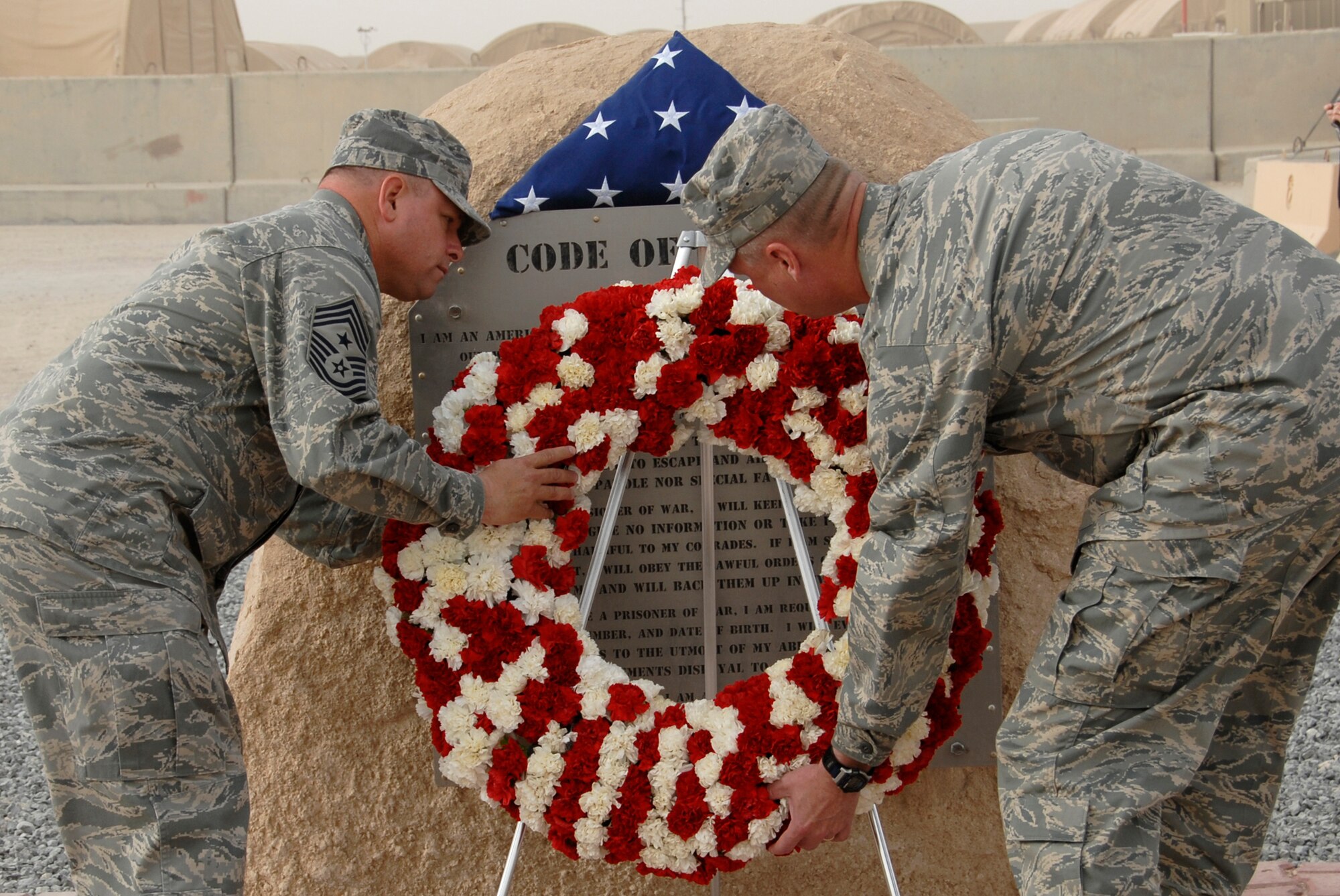 SOUTHWEST ASIA -- Colonel Robert Swisher (right), 386th Air Expeditionary Wing commander, and Chief Master Sgt. Carl Hunsinger, 386th AEW command chief, lay a wreath near the flag poles during a Memorial Day ceremony May 26, 2008 at an air base in the Persian Gulf Region. During the ceremony, a 21-gun salute was conducted along with a laying of a wreath to honor the men and women who have died in military service. (U.S. Air Force photo/ Staff Sgt. Patrick Dixon)