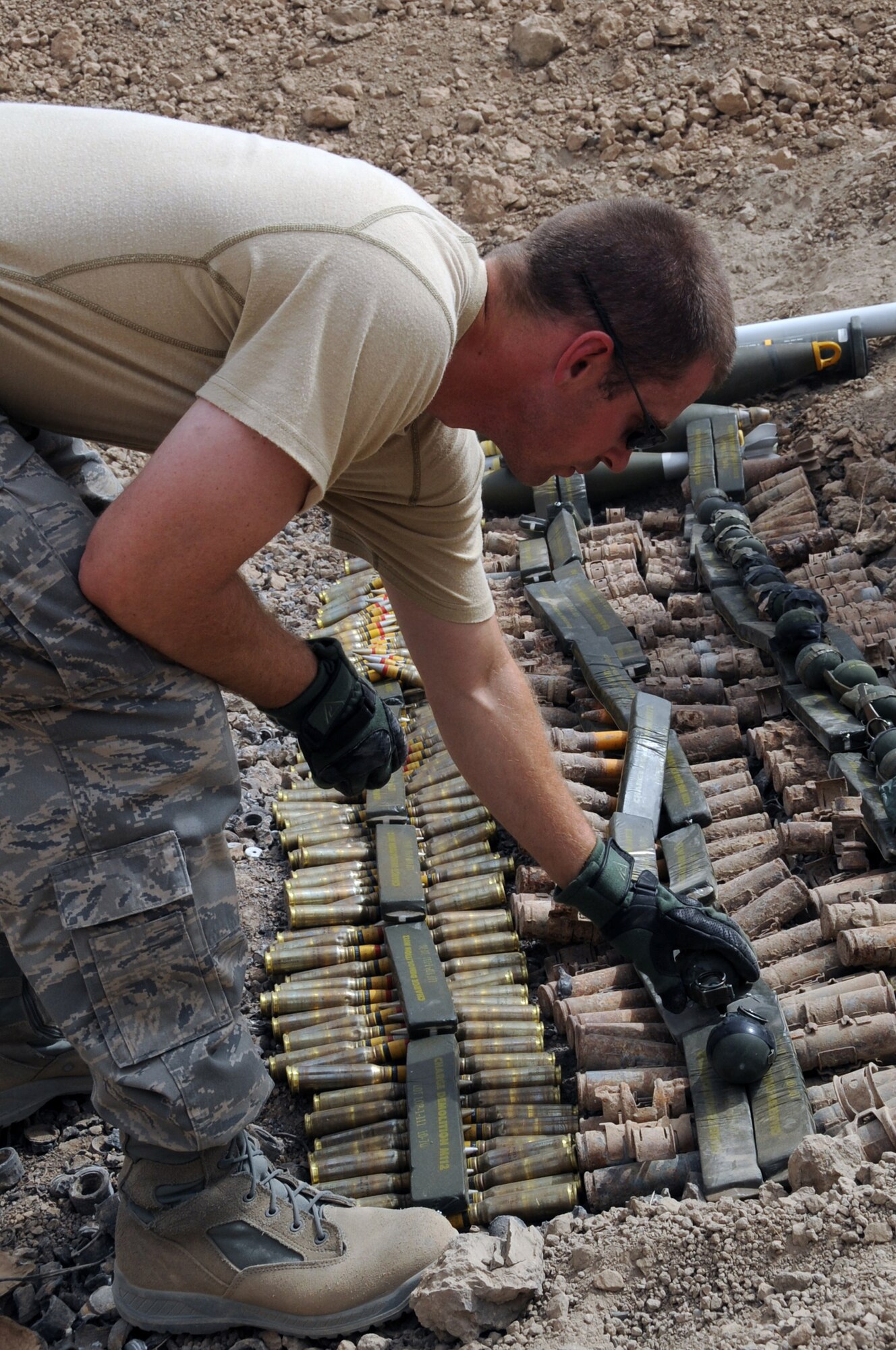 ALI BASE, Iraq -- Senior Airman Noah Cheney, explosive ordnance disposal team member, places unserviceable hand grenades on a disposal site along with other munitions for a controlled detonation here May 27. The team destroyed approximately 500 pounds of hazardous ordnance collected by various coalition forces on Contingency Operating Base Adder and Ali Base. Airman Cheney is deployed to the 407th Expeditionary Civil Engineer Squadron from Mountain Home AFB, Idaho. (U.S. Air Force photo/Tech. Sgt. Sabrina Johnson) 