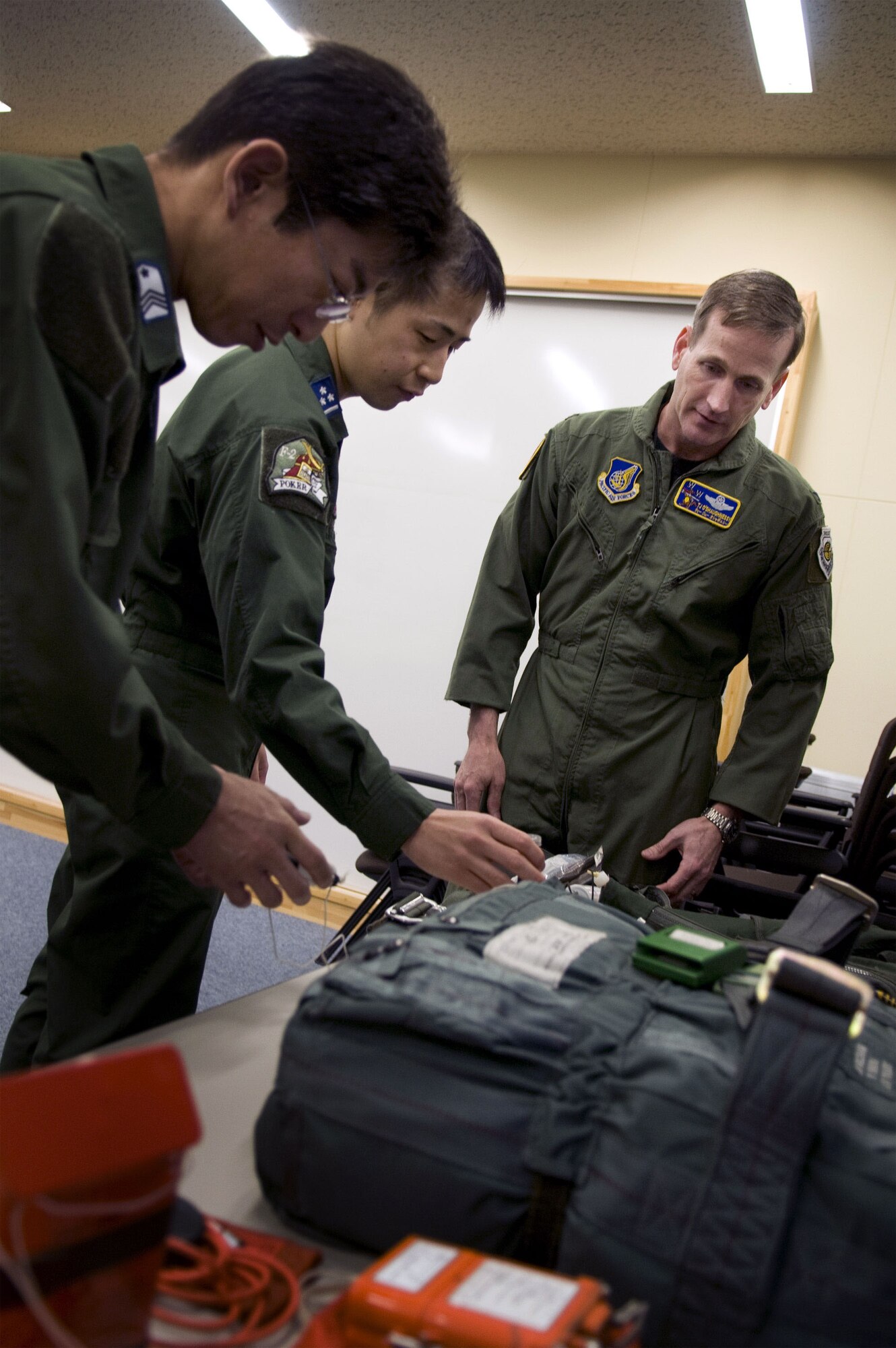 MISAWA AIR BASE, Japan -- Japan Air Self-Defense Force Master Sgt. Yoshinobu Tamori and JASDF Capt. Ryoji Kondo explain the flight gear for their F-2B fighter to Col. T.J. O'Shaughnessy, 35th Fighter Wing commander, at the JASDF 3rd Tactical Fighter Squadron headquarters on May 12, 2008. Colonel O'Shaughnessy flew with JASDF Lt. Col. Masaharu Iwaoka, 3rd TFS commander, that day to familiarize himself with the F-2B's capabilities. (U.S. Air Force photo by Senior Airman Samuel Morse)