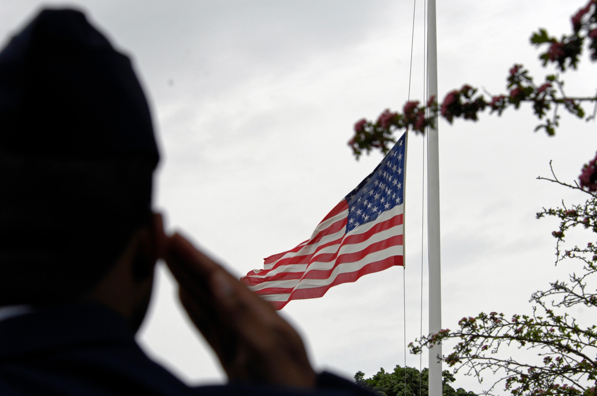 An Airman salutes the colors during the playing of taps May 26 at the Cambridge American Cemetary and Memorial. Memorial Day in England has been held at this site since 1944 when the fathers of the modern Air Force came to pay homage to that "Heroic Band of Airmen" who had gone before. (U.S. Air Force photo by Airman Perry Aston)