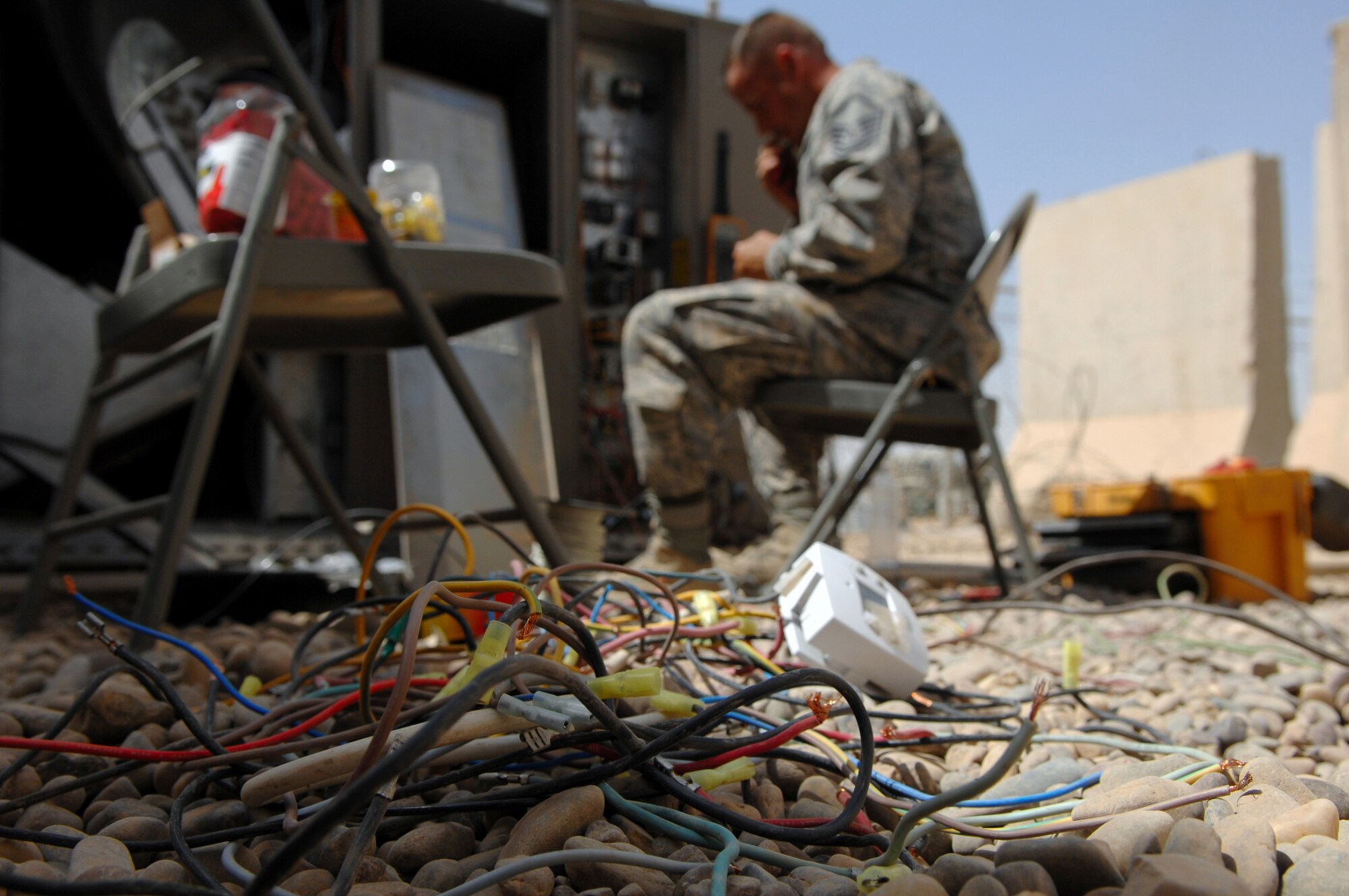 BALAD AIR BASE, Iraq -- Master Sgt. Jason Dean, 332nd Expeditionary Civil Engineer Squadron heating, ventilation and air conditioning special project manager, pulls out old wiring from a packaged air conditioning system here, May 26. The system is used to maintain cool temperatures surrounding mission essential computer equipment in the Air Terminal Operations Center. Most daily temperatures at Balad AB this month have been either at or above 100 degrees Fahrenheit. Sergeant Dean is deployed from F.E. Warren Air Force Base, Wyo. (U.S. Air Force photo/ Senior Airman Julianne Showalter)