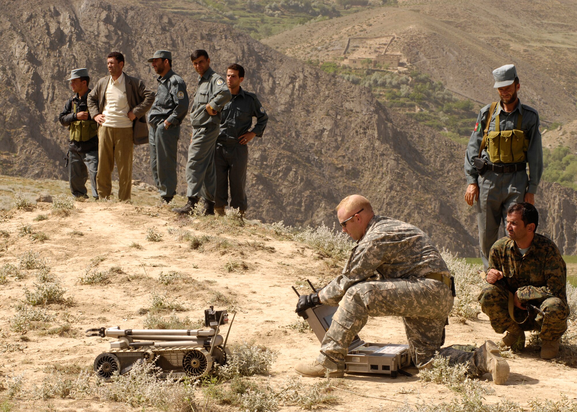 PANJSHIR PROVINCE, Afghanistan – Staff Sgt. Jason Snow, 755th Air Expeditionary Group robot operator, prepares to send a PACBOT to an incident site while local authorities look on.  A local farmer contacted authorities when he found two 107 mm rockets on a timer that were aimed at a coalition forward operating base.  Snow is deployed from 1st Civil Engineer Squadron EOD Flight, Langley Air Force Base, Va. (U.S. Air Force Photo by Master Sgt. Demetrius Lester)