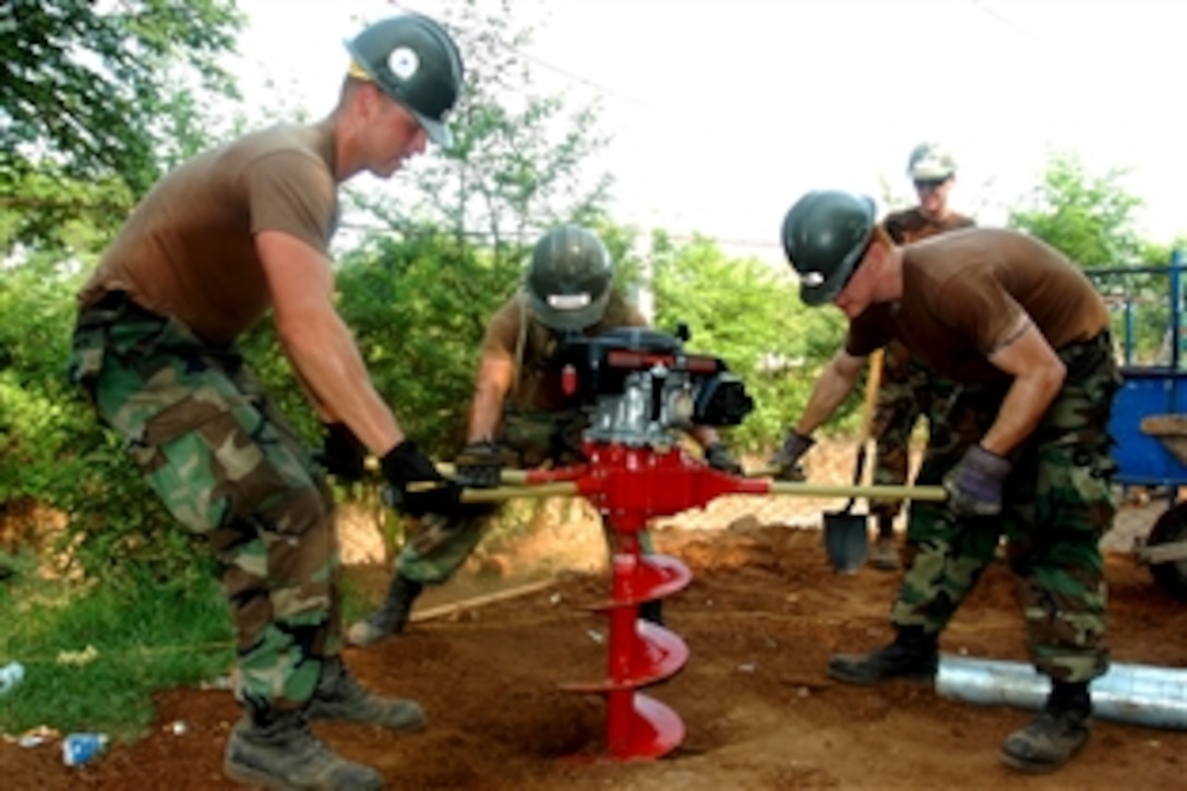 U.S. Navy Petty Officers 2nd Class Roberto Duajardo and 3rd Class Justin Lewis and Seaman William Stimson dig a hole with an auger to insert posts for new fencing at Canton La Sunza school in El Salvador as part of Continuing Promise 2008, May 19, 2008. The three Seabees are assigned to Construction Battalion Maintenance Unit 303, embarked aboard the amphibious assault ship USS Boxer. 