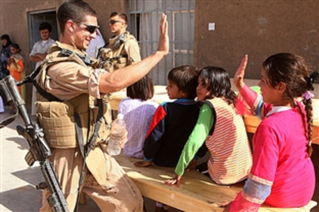 U.S. Marine Lance Cpl. Alex C. Brilla high-fives a young Iraqi girl during a school supply mission, May 23, 2008, in western Al Anbar province, Iraq. The platoon has been visiting and supplying the school for more than a month.