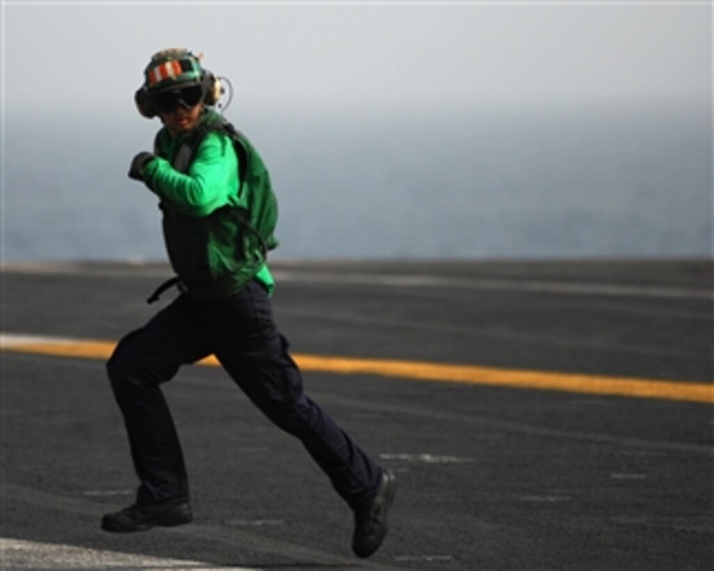 U.S. Navy Aviation Boatswain's Mate Petty Officer 3rd Class Michael Kwon sprints back across the landing area after checking the condition of an arresting cable during fixed-wing aircraft recovery operations aboard the Nimitz-class aircraft carrier USS Abraham Lincoln (CVN 72) while underway in the Arabian Gulf on May 20, 2008.  The Lincoln is deployed to the U.S. Navy 5th Fleet area of responsibility to support maritime security operations.  