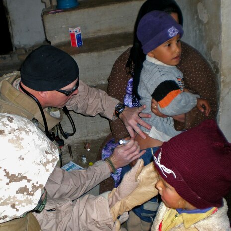 Petty Officer 2nd Class Adam F. Kinney, a Navy Corpsman with Company E, 2nd Battalion, 24th Marine Regiment, Regimental Combat Team 1, gives an Iraqi Child a shot during a routine patrol. Kinney is assigned to Echo Co. for their seven-month deployment and will return to his parent command, 4th Tank Battalion in Fort Knox, Ky., upon his arrival.
