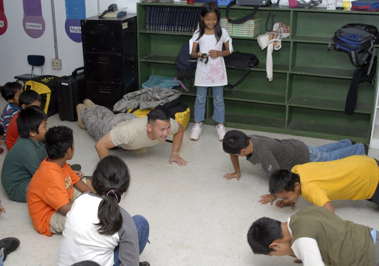 Technical Sgt. Maxwell Pontenila part of the 36th Services Squadron, show Mrs. Herrera's third grade class a correct military push-up.  Sgt. Pontenila was one of five military members speaking to the class about the importance of school, and the importance of starting your education off correctly. (U.S. Air Force photo by Staff Sgt. Patrick Mitchell)  