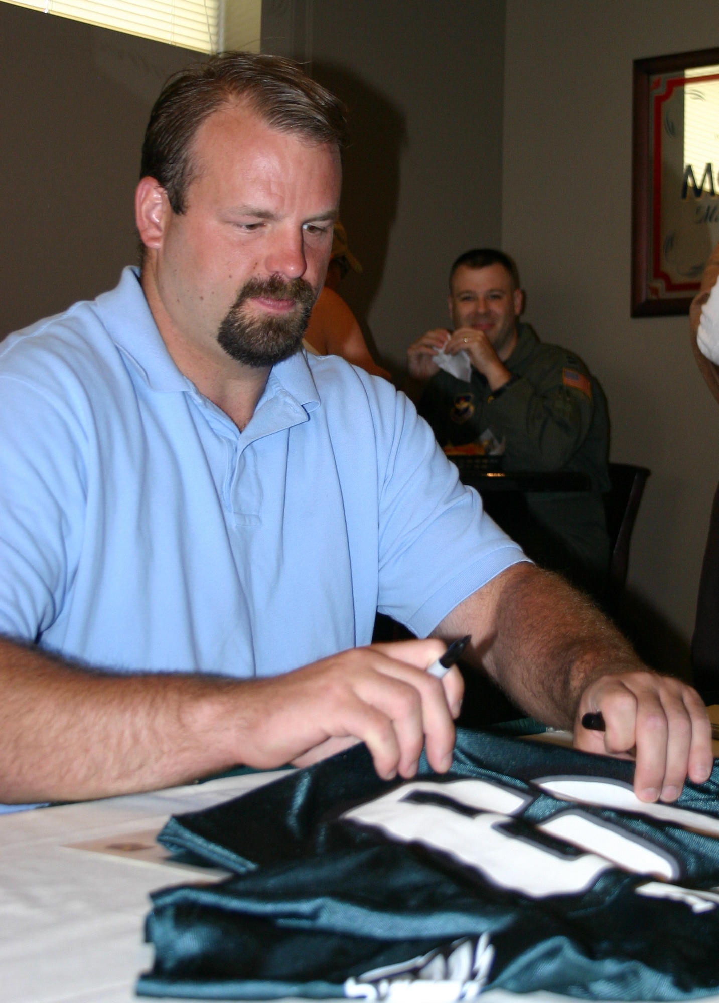 Jon Runyan, Offensive Tackle for the Philadelphia Eagles signs a jersey owned by a McGuire Airman at Pudgy's lounge on May 28. The 13-year NFL veterans' visit helped McGuire Airmen celebrate Air Force Week in Philadelphia by allowing Airmen to spend time with one of the Philadelphia Eagles offensive weapons.  McGuire returned the favor by allowing the city of Philadelphia to spend the week with some of America's finest weapons...American Airmen. (U.S. Air Force photo/Master Sgt. Dwayne Gordon)