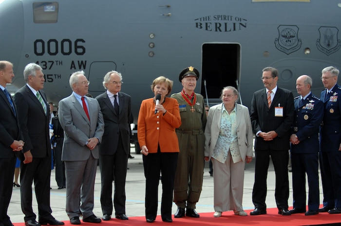 BERLIN, Germany — German Chancellor Dr. Angela Merkel addresses the audience during a Berlin Airlift 60th anniversary ceremony at the 2008 Berlin Air Show May 27. The ceremony, staged in front of the "Spirit of Berlin" C-17 Globemaster from Charleston AFB, S.C., highlighted Col. (retired) Gail Halvorsen, The Berlin Candy Bomber, (pictured on her right) and other veterans of the airlift. (U.S. Air Force photo/Tech Sgt. Corey Clements)