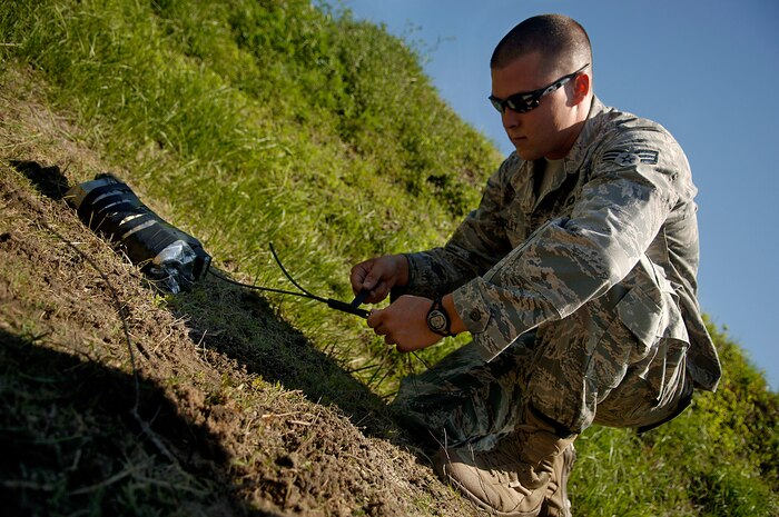 Senior Airman Johnathan Baxley wraps an explosive charge around a block of C-4 and stick of outdated and dangerous TNT at a secure location on Charleston AFB May 22. Airman Baxley is an EOD equipment supervisor with the 437 CES. (U.S. Air Force photo/Senior Airman Nicholas Pilch)