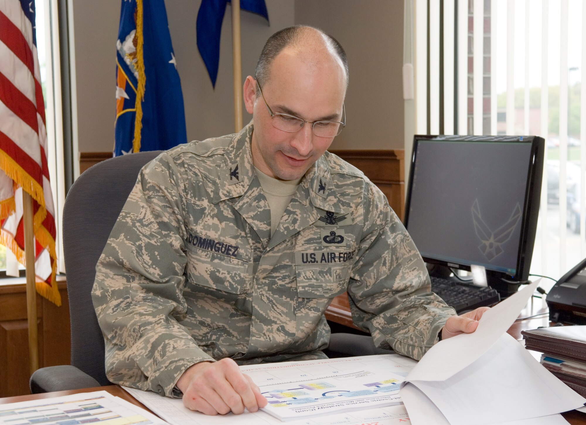 HANSCOM AFB, Mass. -- New 350th Electronic Systems Wing Commander Col. Robert Dominguez reviews organizational charts and group objectives in his office on a recent afternoon. According to Colonel Dominguez, focusing on maintaining an efficient acquisition process and further developing his workforce are among his foremost goals. (U.S. Air Force photo by Rick Berry)