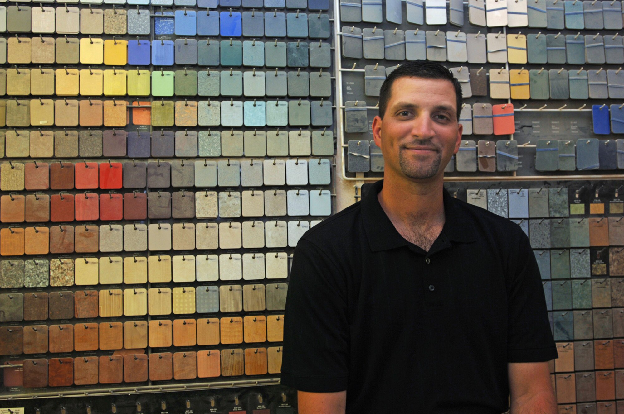 Behind Senior Master Sgt. Kurt Smith are samples of the many textures that Global Engineering customers can choose for the interior of their aircraft.