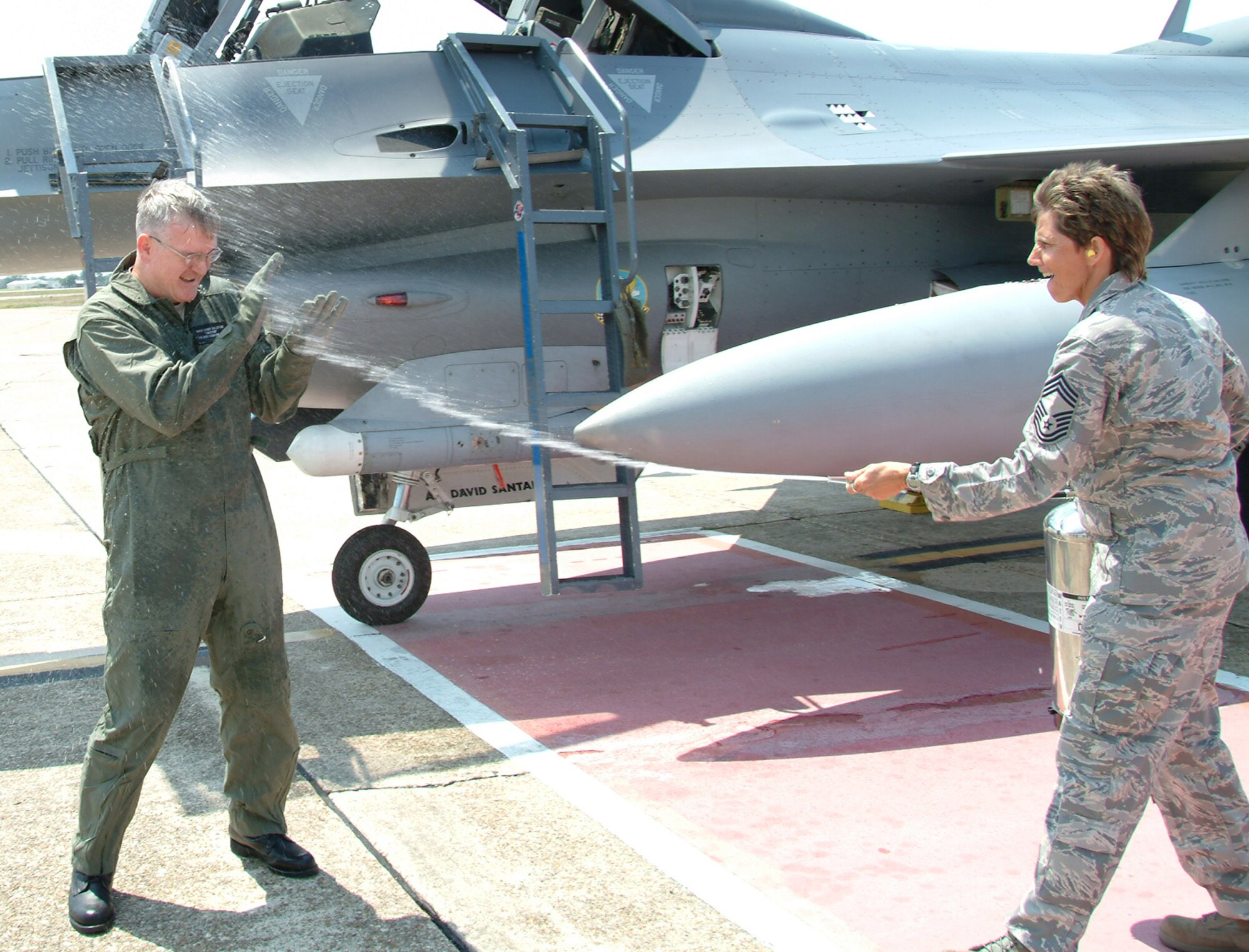 Chief Master Sgt. Randy Salefske, 53d Wing command chief, gets hosed down by Chief Master Sgt. June Robbins, 53d Test Management Group chief, after his F-16 incentive flight May 28 at Eglin Air Force Base, Fla.  It was the first time the chief took to the skies in an Air Force fighter in his 30-year career.  The chief ended his career with the 53d Wing at a retirement ceremony May 30.  Photo by Staff Sgt. Samuel King Jr.