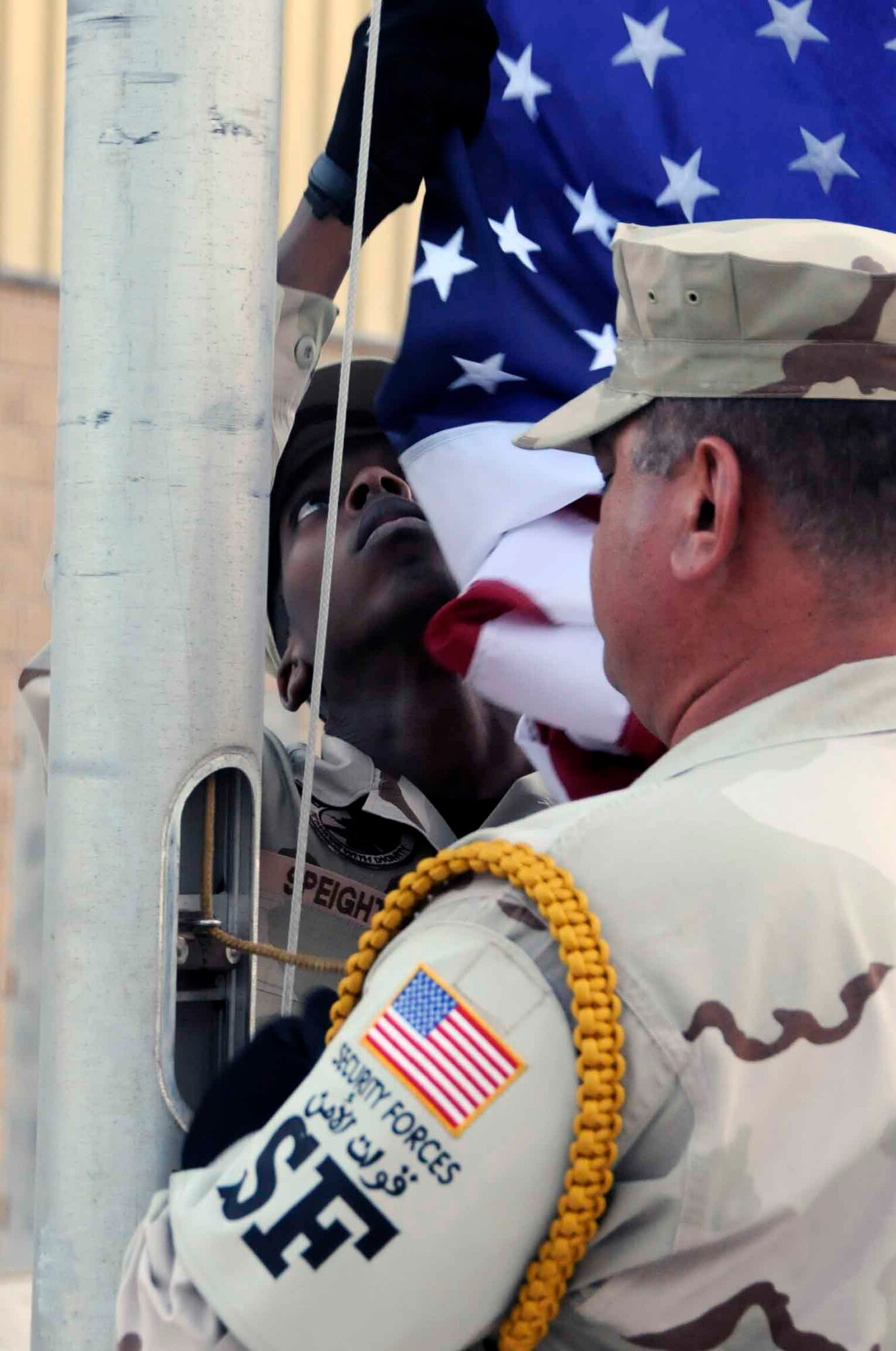 SOUTHWEST ASIA—Staff  Sgt. James Speight, 379th Expeditionary Security Forces Squadron, base honor guard, detaches the U.S. flag, after Tech. Sgt. Tom Walker, 379th Expeditionary Security Forces Squadron lowered it from the flag pole May 26.  After the flag is brought down, it is folded with the help of two other honor guard members. (U.S. Air Force photo/Senior Airman Domonique Simmons)