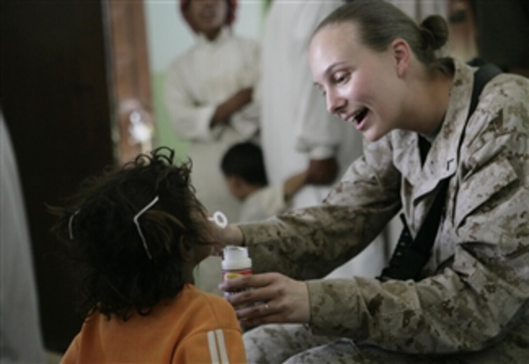 U.S. Marine Corps Pfc. Jessica Etterman, an intelligence analyst with 1st Intelligence Battalion, Regimental Combat Team 1, shows an Iraqi child how to blow bubbles during a cooperative medical engagement in Zaidon, Iraq, on May 22, 2008.  