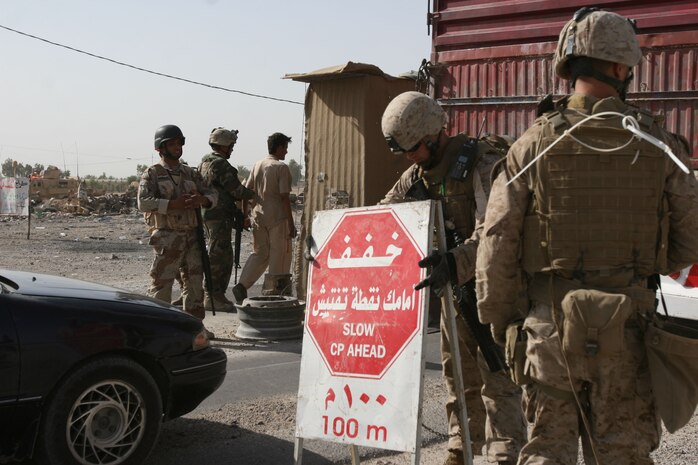 Marines with 2nd Battalion, 3rd Marine Regiment, Regimental Combat Team 1, set up road signs at a vehicle check point, May 29, in Karma, Iraq, before kicking off Operation Gravel Dump. The Marines of Company F assisted Iraqi Security Forces conducting vehicle searches. The ISF took charge of the operation, checking gravel trucks for weapons caches that may have been hidden inside the trucks cargo. (Photo by Cpl. Chadwick deBree)