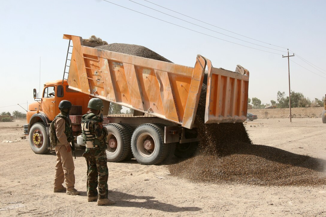 Iraqi Army soldiers scan for any weapons as a gravel truck dumps its cargo May, 28, during Operation Gravel Dump in Karma, Iraq. Local Iraqi Security Forces partnered with Marines from Company F, 2nd Battalion, 3rd Marine Regiment, Regimental Combat Team 1, to search vehicles for weapons caches that may be hidden in them. (Photo by Cpl. Chadwick deBree)
