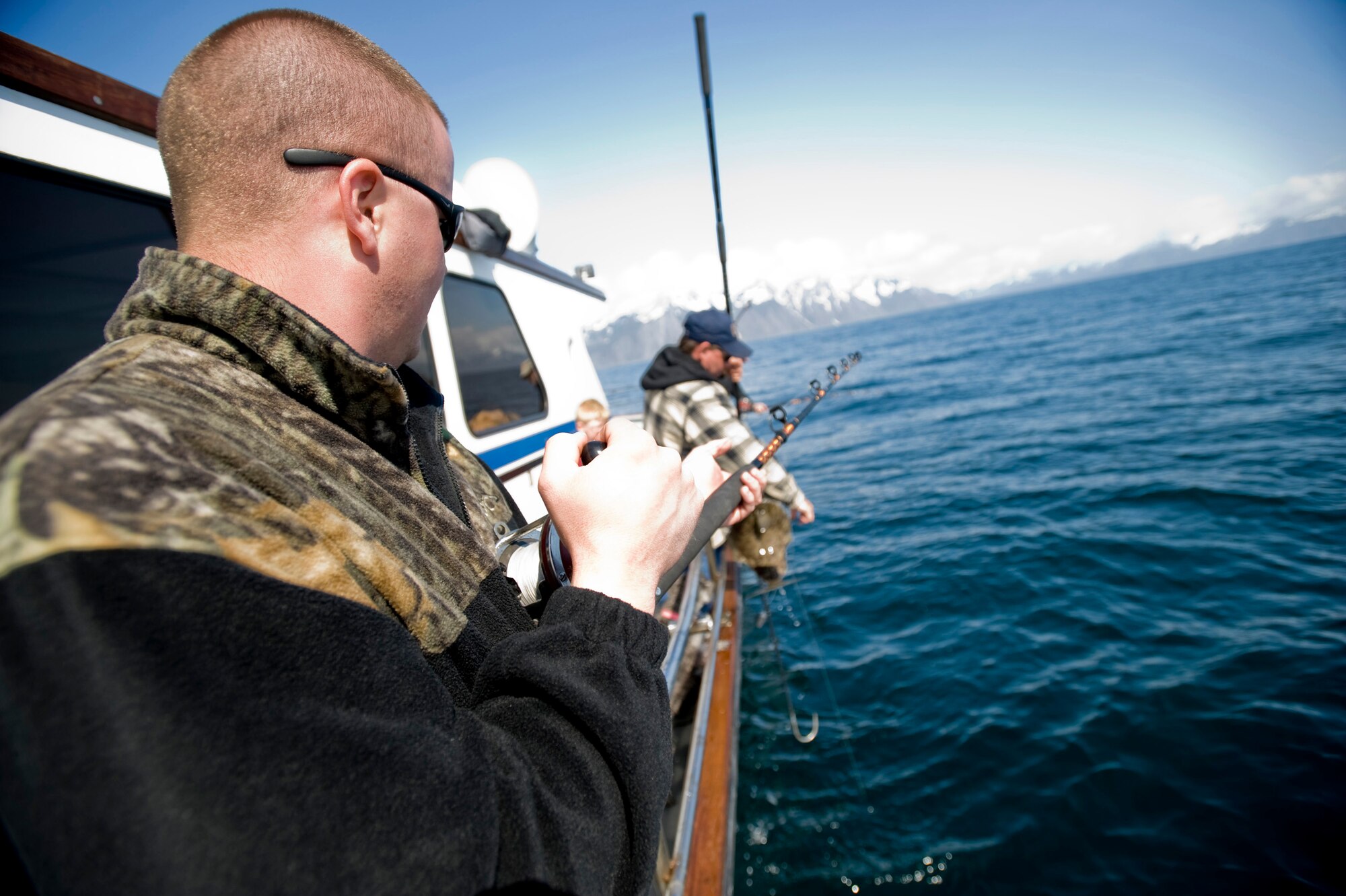 Senior Airman Timothy Jeffrey, 354th Security Forces Squadron, reels up a halibut that he caught during the tournament. Airman Jeffrey was aboard the Rainisong, one of 33 boats that participated in the tournament. (U.S. Air Force Photo/ Senior Airman Jonathan Steffen)