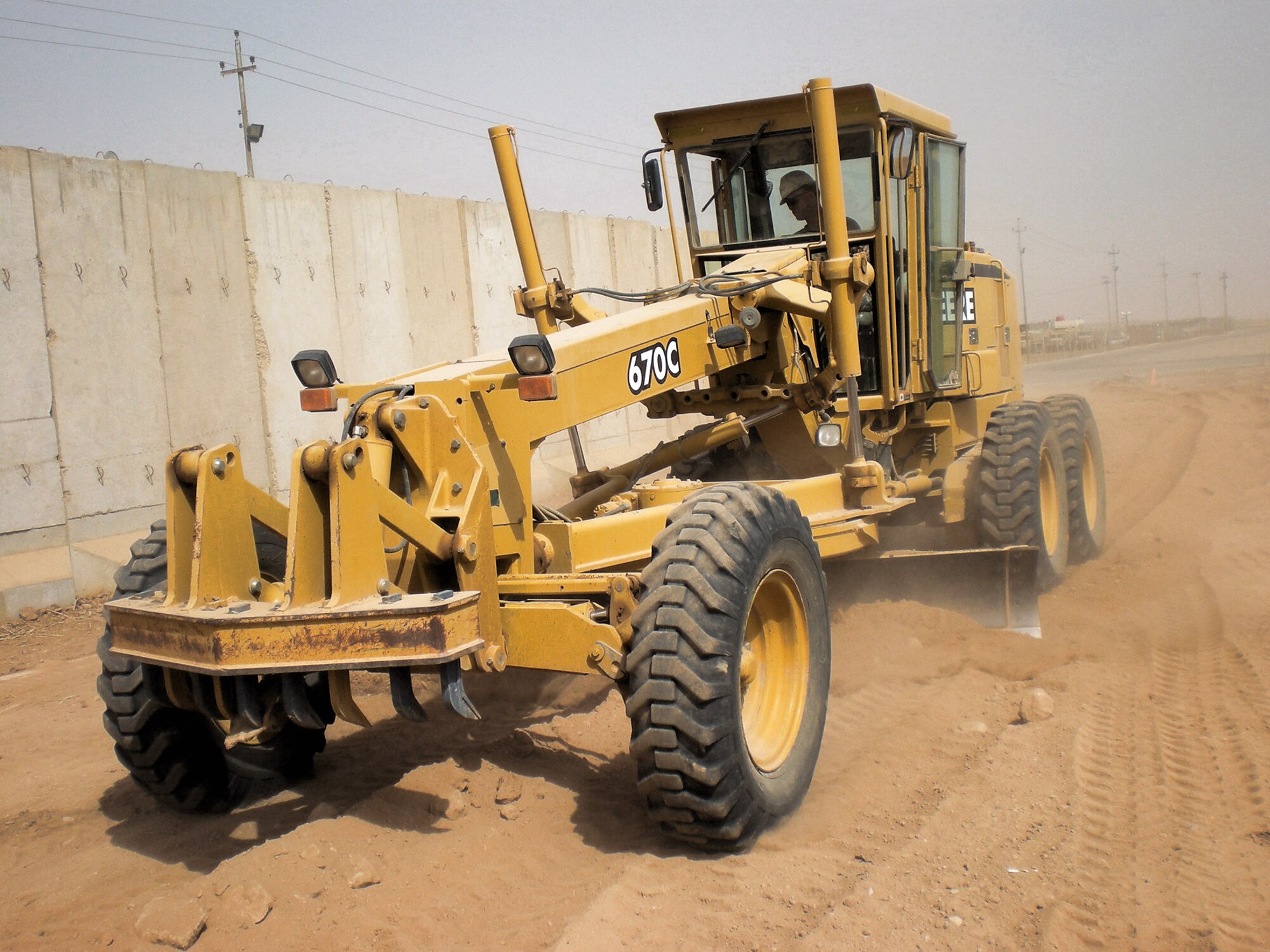 Staff Sgt. Stephen Hansen grades an area of dirt to prepare it for pouring of a concrete pad at Forward Operating Base Caldwell, Iraq. Airmen from the 732 ECES Dirt Boys poured almost 1,577 cubic yards of concrete during three separate pad projects at the FOB. These pads will allow the Soldiers to perform maintenance on their vehicles without having to be in the dirt and mud. Sergeant Hansen is deployed from Holloman Air Force Base, N.M. Sergeant Hansen is a heavy equipment operator with the 732nd Expeditionary Civil Engineer Squadron. (U.S. Air Force photo/Staff Sgt. Josh Jeffreys) 