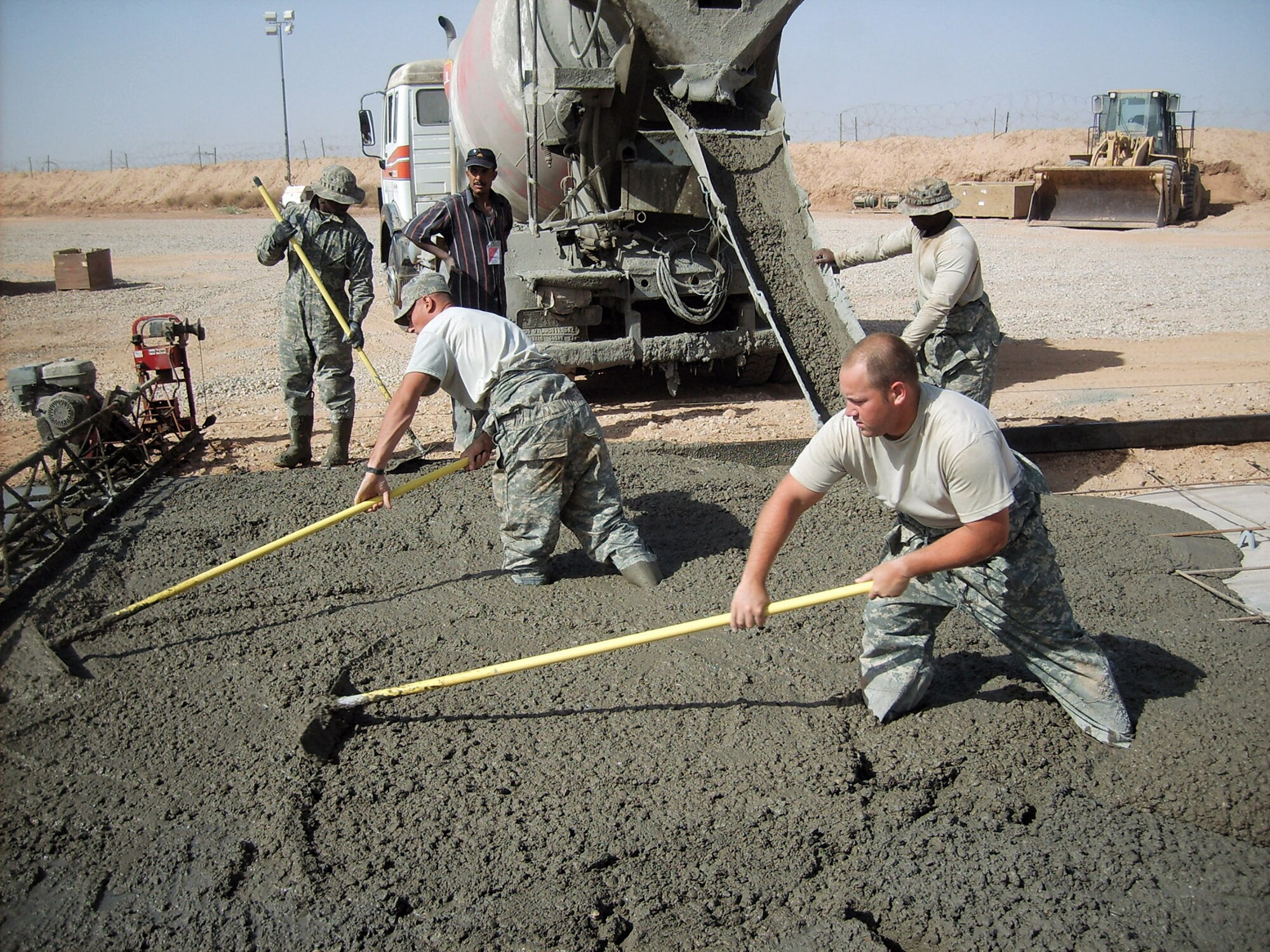 Senior Airmen Dan Smith, Deion Williams, Airmen 1st Class George Farrington and Richard Simmons pour and rake concrete pads during a project to improve Forward Operating Base Caldwell, Iraq. The concrete pads will allow Soldiers to perform maintenance on their vehicles without having to lay in the mud. All are heavy equipment operators with the 732nd Expeditionary Civil Engineer Squadron. (U.S. Air Force photo/Staff Sgt. Josh Jeffreys) 