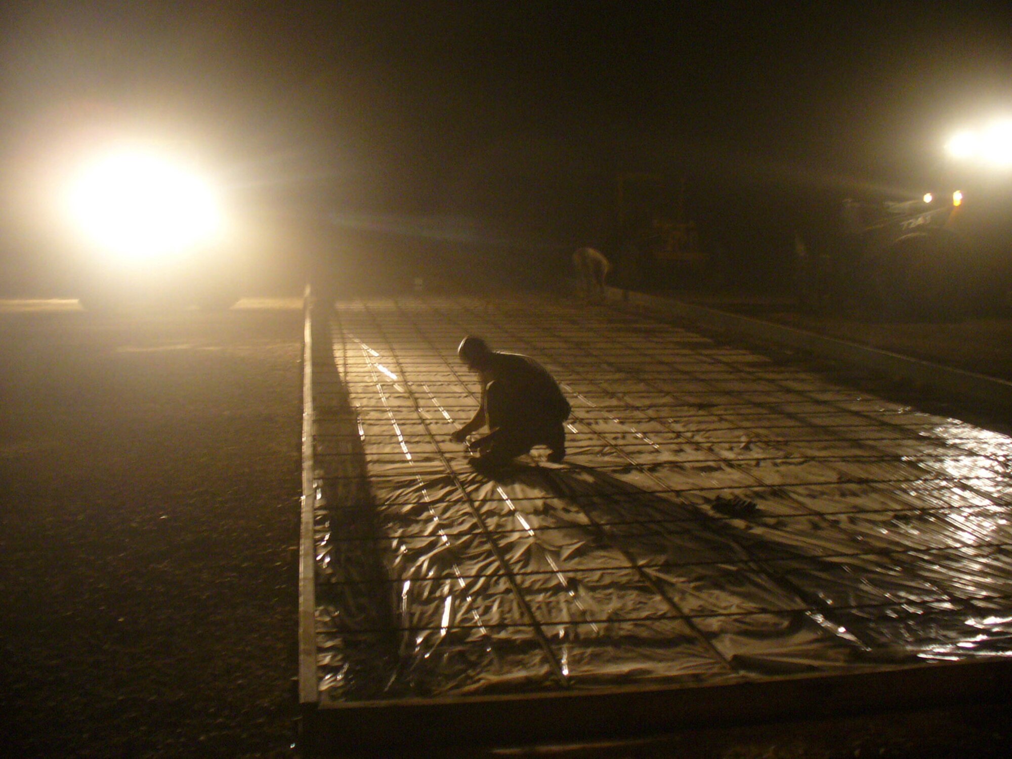 Tech. Sgt. Chris Moffett ties down rebar under equipment lights during a nighttime dust storm at Forward Operating Base Caldwell, Iraq. The Airmen worked in shifts in order to finish the project at FOB Caldwell in minimal time. The concrete pads allow Soldiers a place to work on their vehicles without having to be in the dirt and mud. Sergeant Moffett is a heavy equipment operator with the 732nd Expeditionary Civil Engineer Squadron. (U.S. Air Force photo/Staff Sgt. Stephen Hansen) 