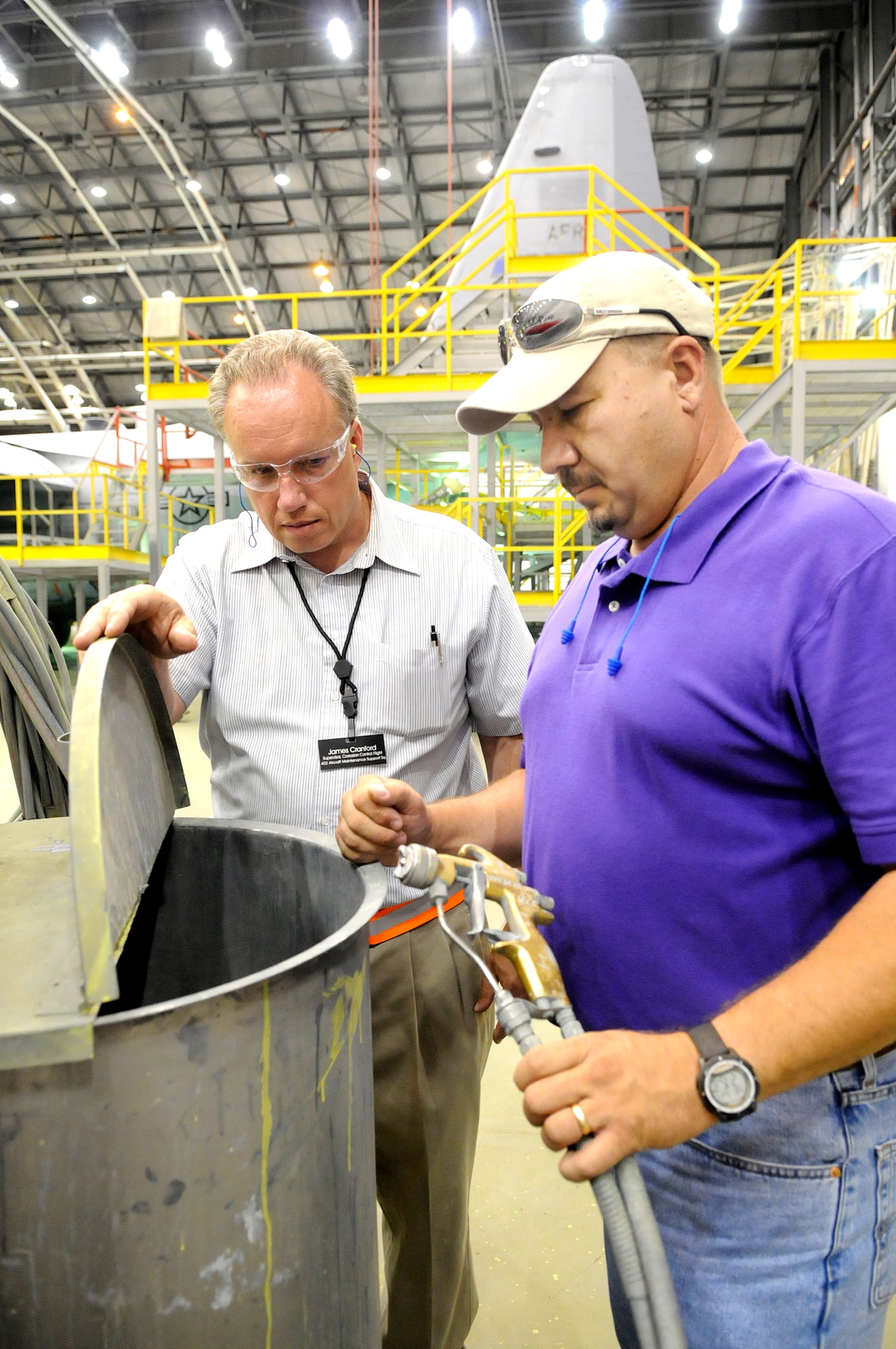 James Cranford and Todd Lavender discuss the air assisted airless paint system. U. S. Air Force photo by Sue Sapp