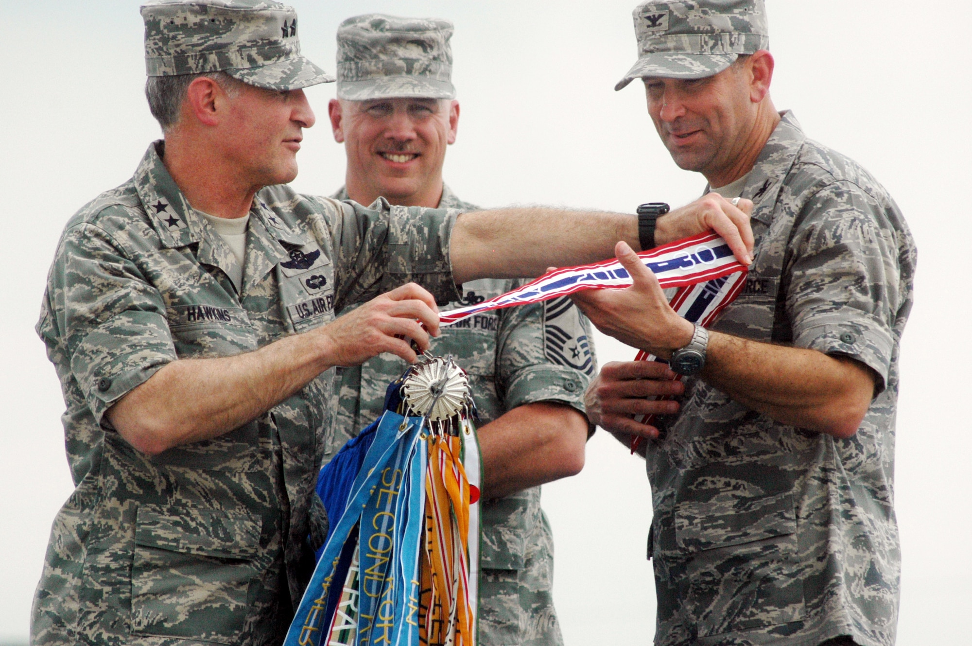 Maj. Gen. James Hawkins, 18th AF/CC attaches the Air Force Meritorious Unit Award decoration to the 19th ARG guidon as CMSgt. Kevin Hamilton and Col. Chris Bence look on. U. S. Air Force photo by Sue Sapp
