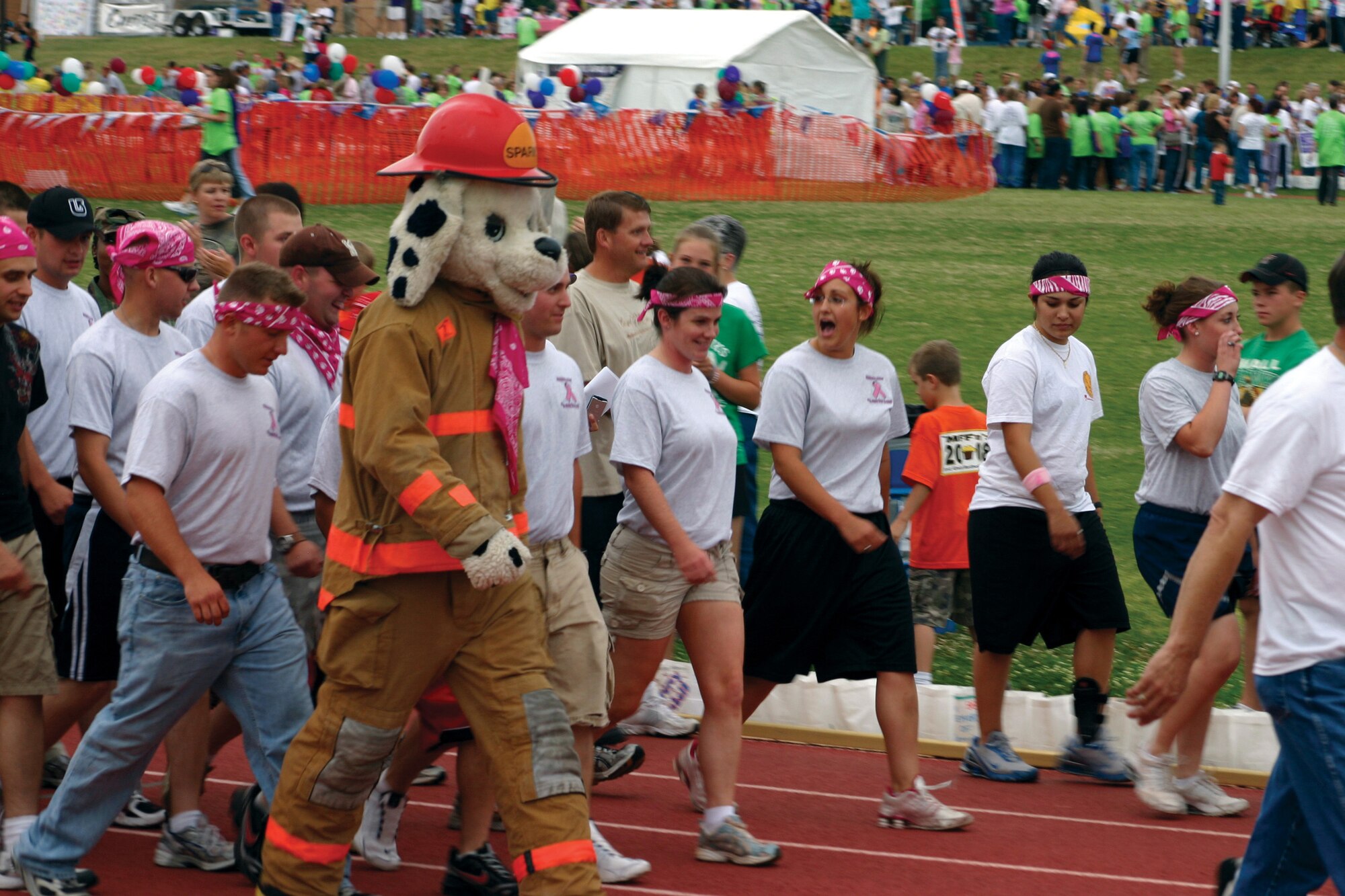 A rowdy crew of Pink Panthers from the 312th Training Squadron walks alongside Sparky the Firedog during the Relay for Life May 16. Pink is the color of cancer awareness. Thirty-two teams from Goodfellow Air Force Base volunteered to walk in the relay, which raised money in the search for a cure. (U.S. Air Force photo by Lt. Col. Terry Smith)