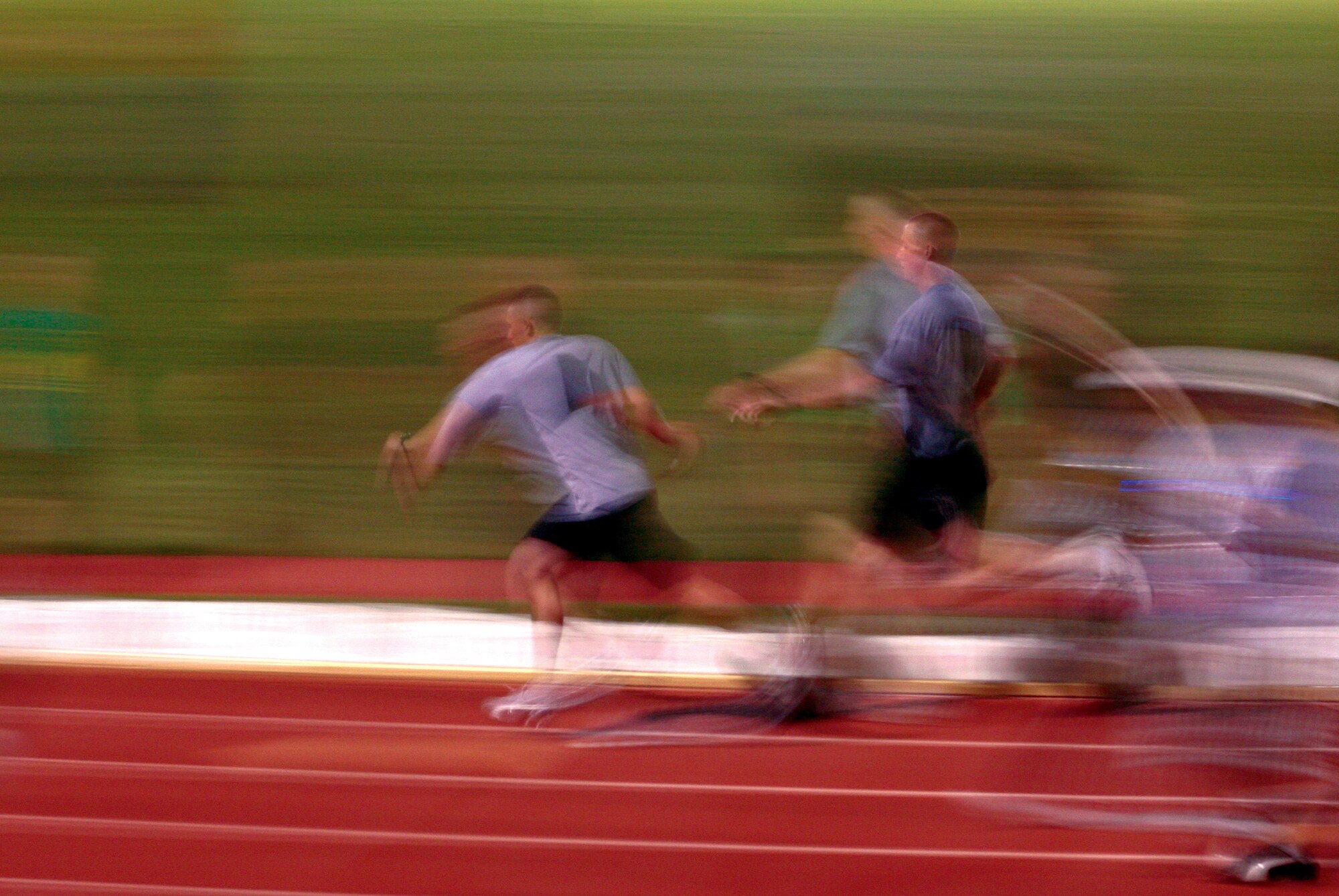 Members of the 344th Military Intelligence Battalion are a blur as they pass their baton during the relay. The Army’s A Company ran a total of 500 laps in support of the search for a cure for cancer. (U.S. Air Force photo by Lt. Col. Terry Smith)