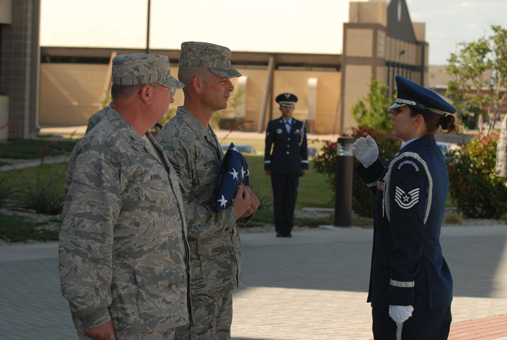 Chief Master Sgt. Paul Moreau, former 17th Training Wing command chief master sergeant (center) accepts an American flag from Tech. Sgt. Karen Harr, 17th Medical Operations Squadron, while Col. Richard Ayres, 17 TRW commander, looks on during a special retreat ceremony May 15. Chief Moreau heads to Keesler Air Force Base, Miss., to serve as the 2nd Air Force command chief master sergeant. (U.S. Air Force photo by Staff Sgt. John Barton)